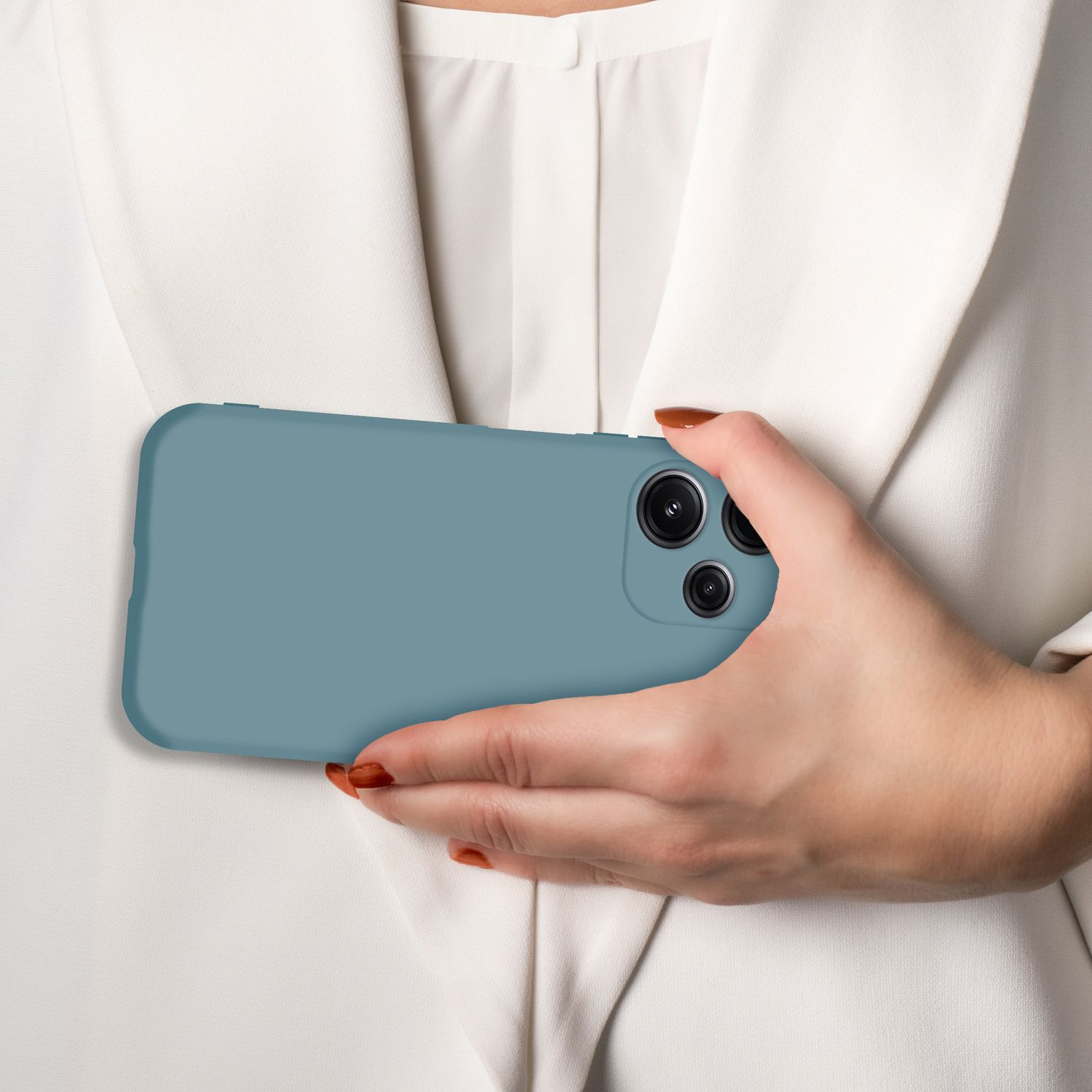 Eine Hand hält ein blaues Handy vor einem weißen Blazer.
