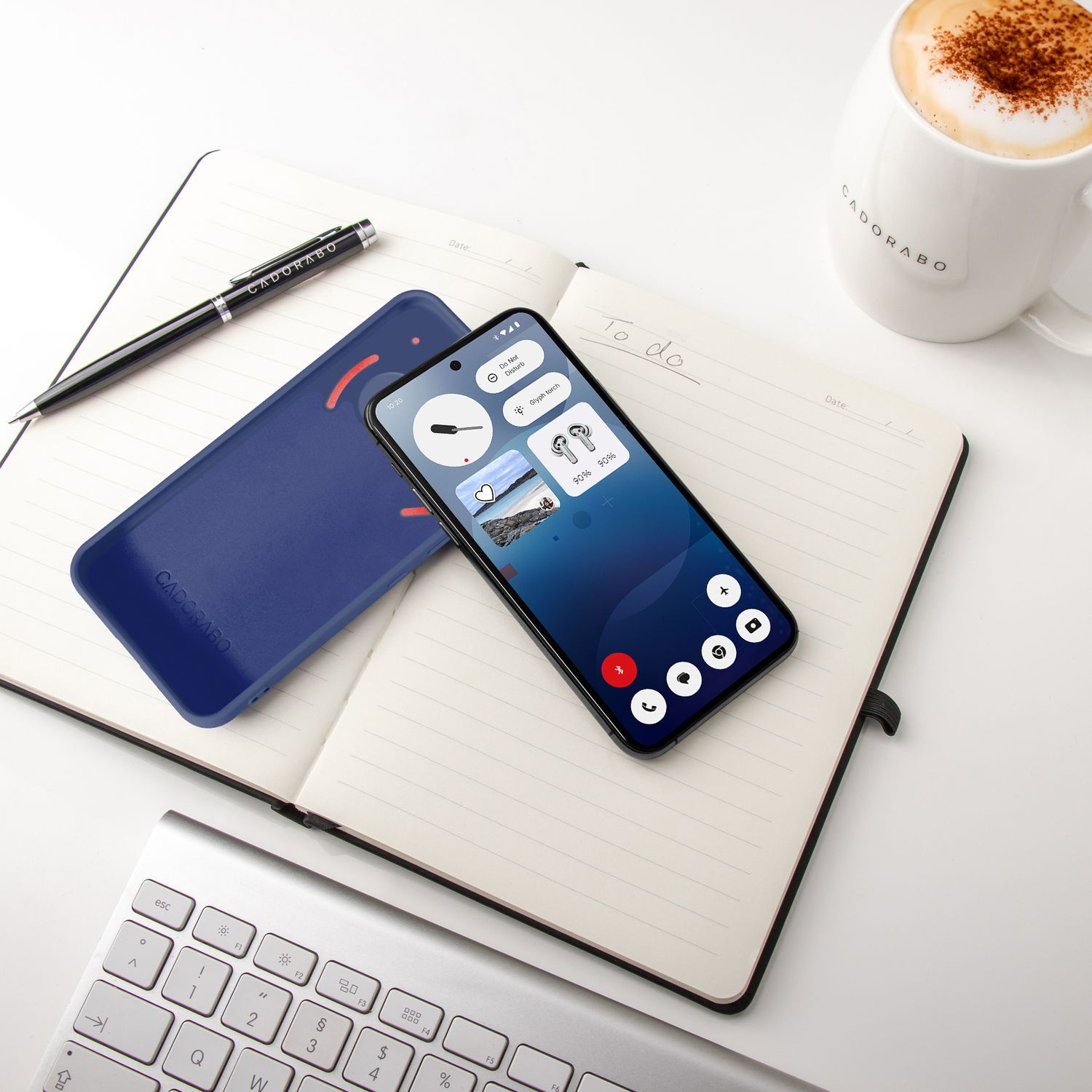 Ein Smartphone mit blauer Hülle liegt auf einem Notizbuch neben einer Tasse Kaffee.