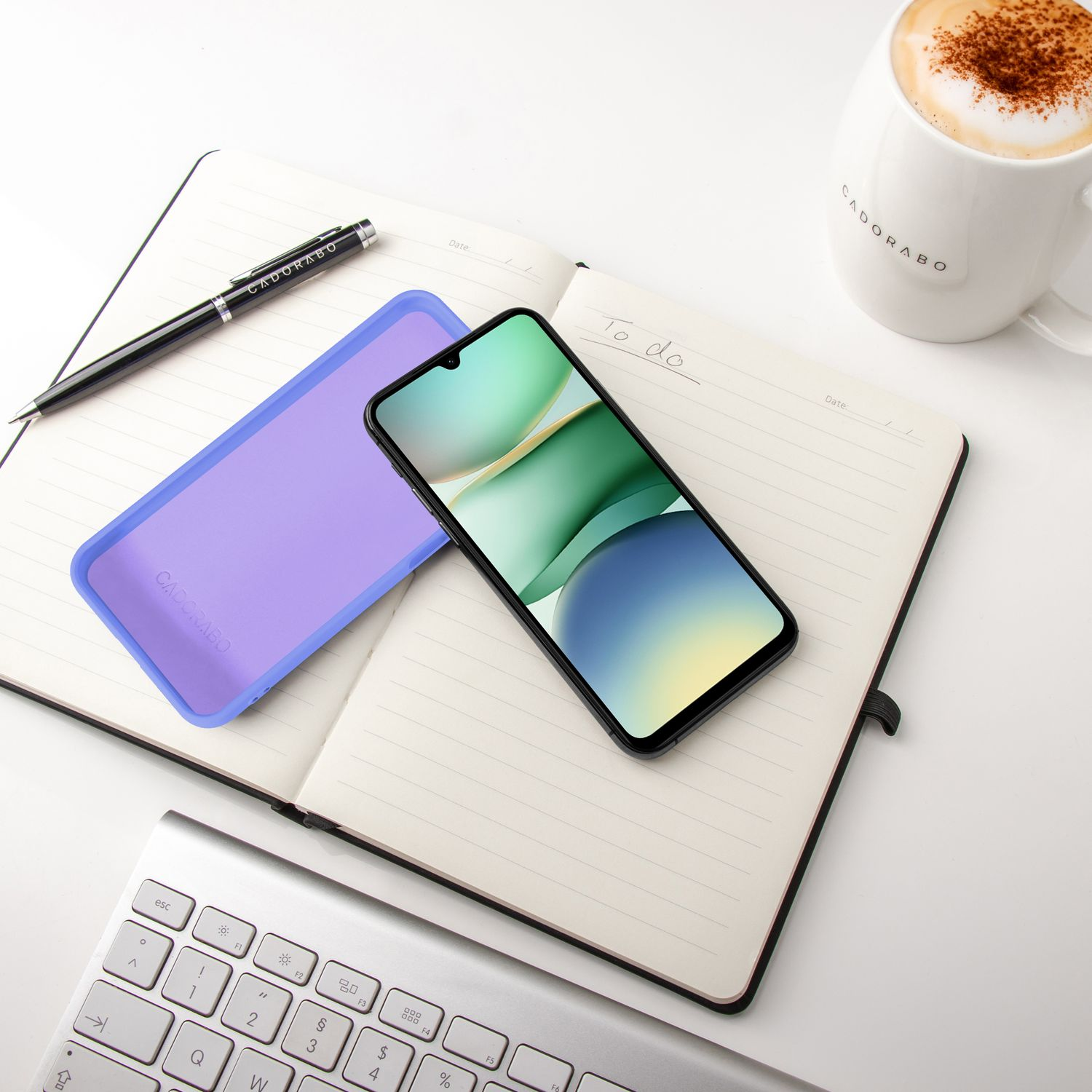 Ein Notizbuch mit Stift, Handy, Tastatur und Kaffee. Alles auf weißem Hintergrund.