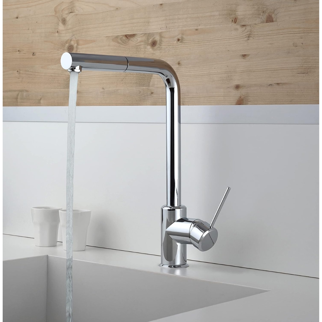 Rubinetto cromato con getto d'acqua in un lavandino, parete in legno sullo sfondo.