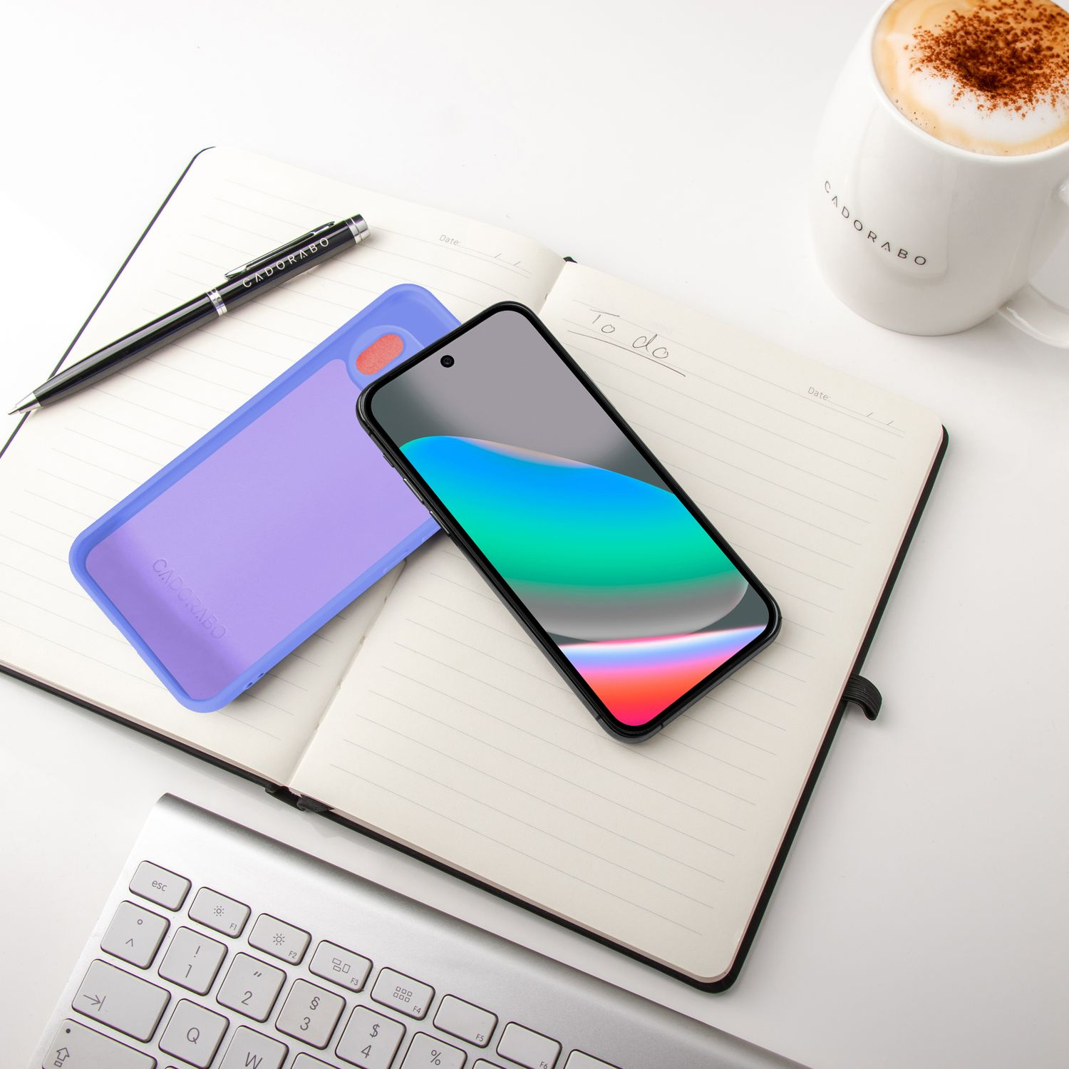 Ein aufgeschlagenes Notizbuch mit Stift, Handyhülle, Smartphone und Kaffee.