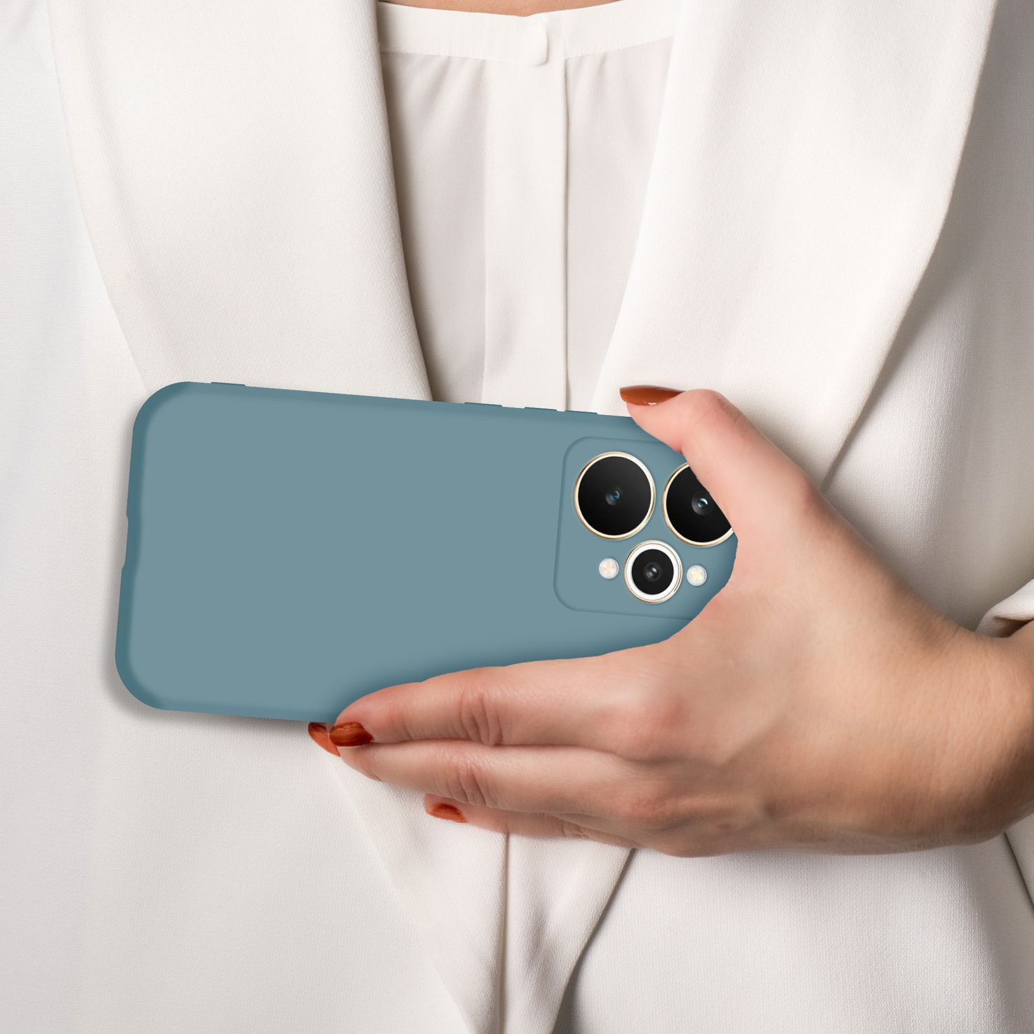Eine Hand hält ein blaues Handy mit drei Kameras vor einem weißen Hemd.