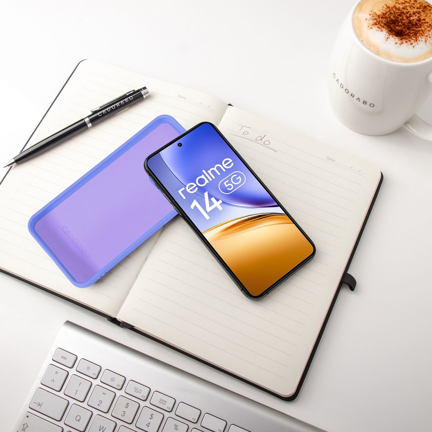 Ein Smartphone liegt auf einem Notizbuch neben einer Tasse Kaffee und einer Tastatur.