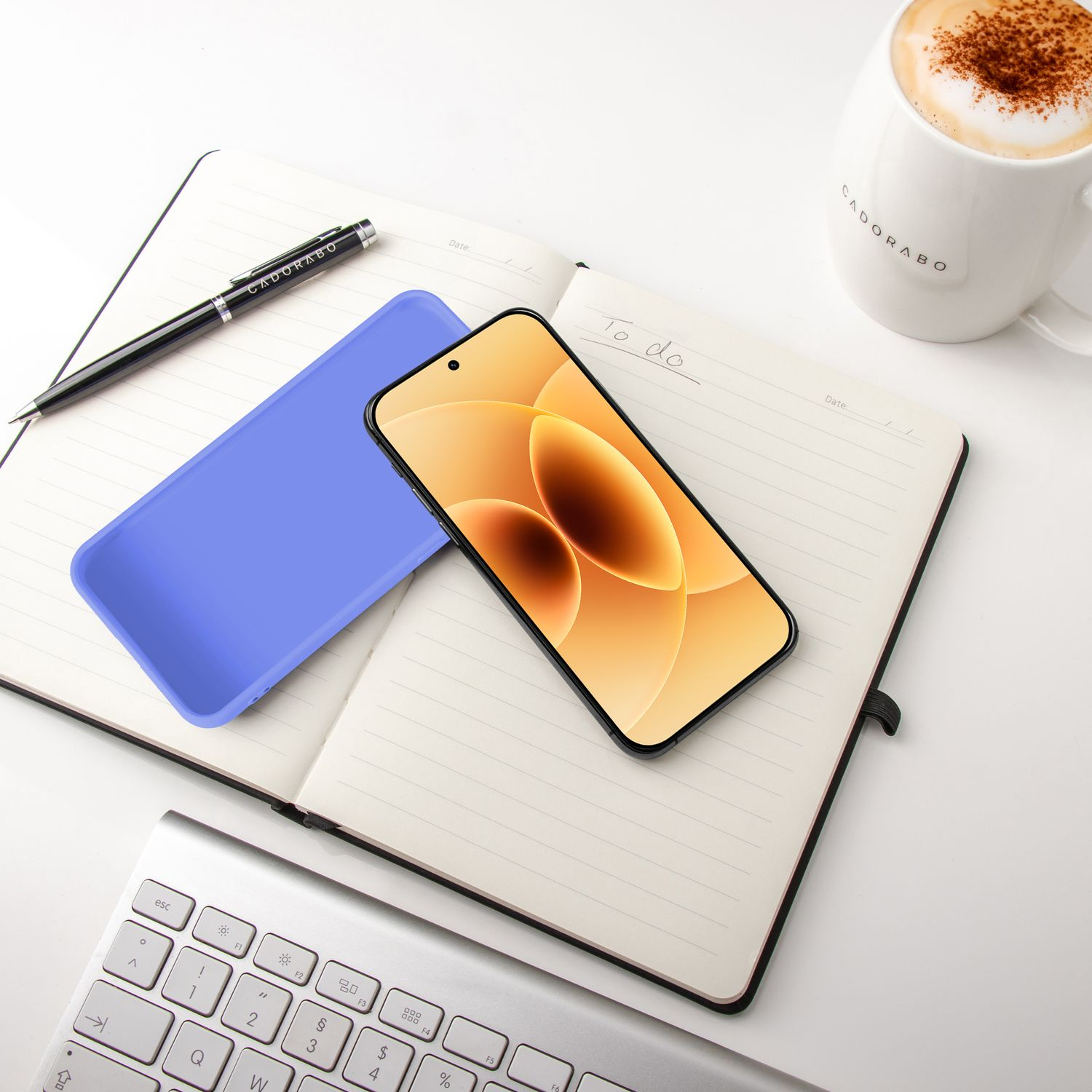Ein Smartphone liegt auf einem Notizbuch neben einer Tasse Kaffee.