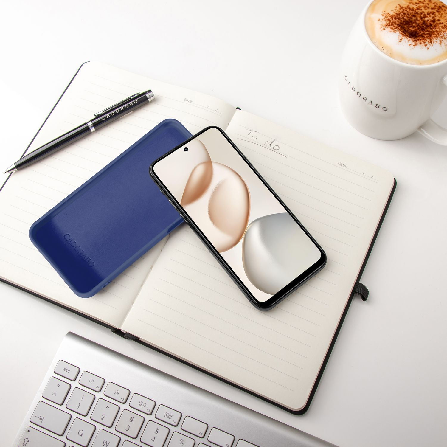 Notizbuch mit Stift, Handy, Tastatur und Kaffee auf weißem Hintergrund.