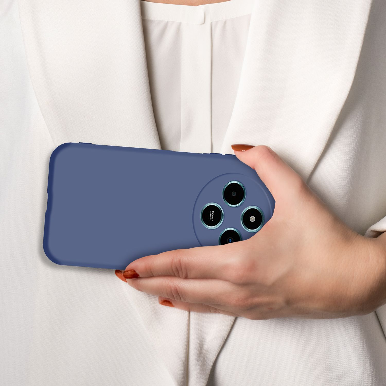 Eine Hand hält ein blaues Handy mit vier Kameras vor einem weißen Hemd.