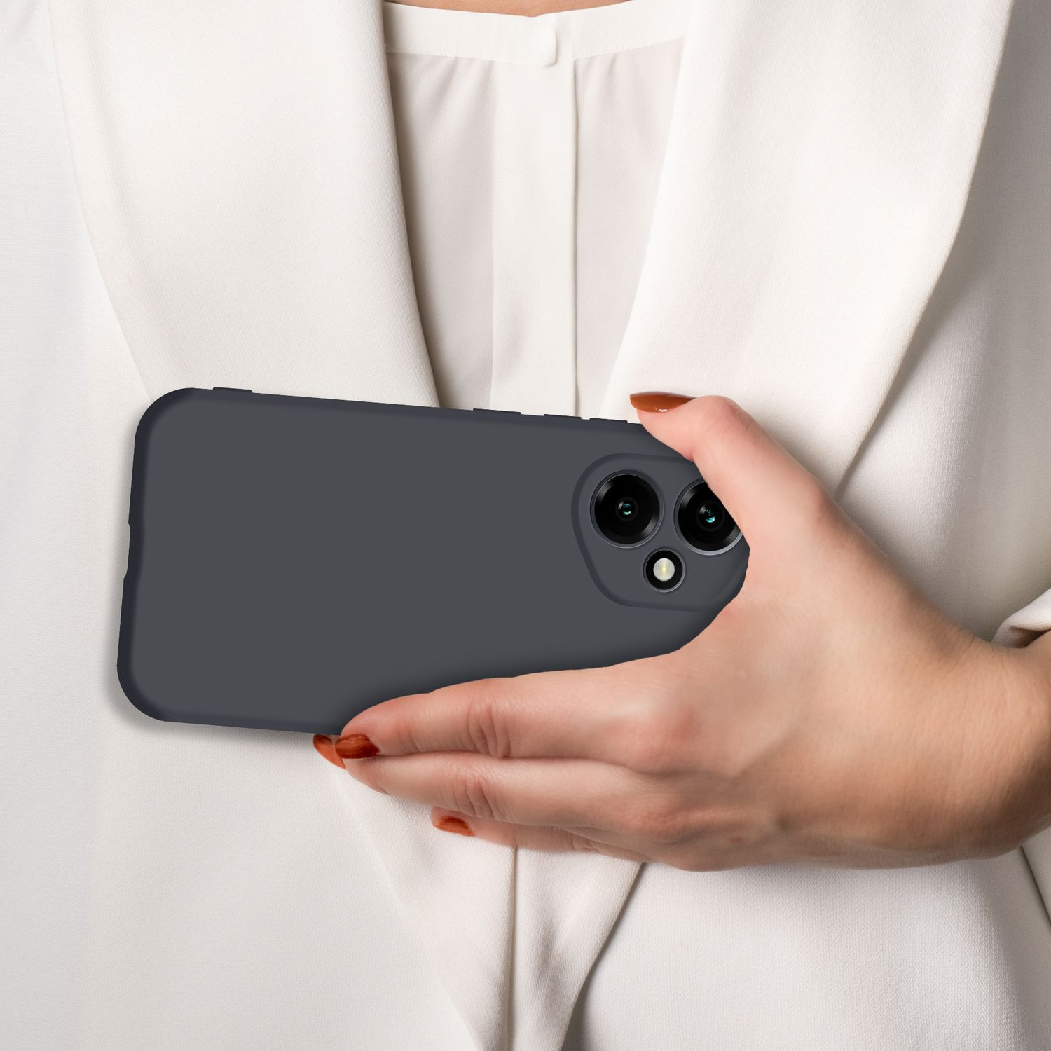 Eine Hand hält ein dunkles Handy mit zwei Kameras vor einem weißen Hemd.