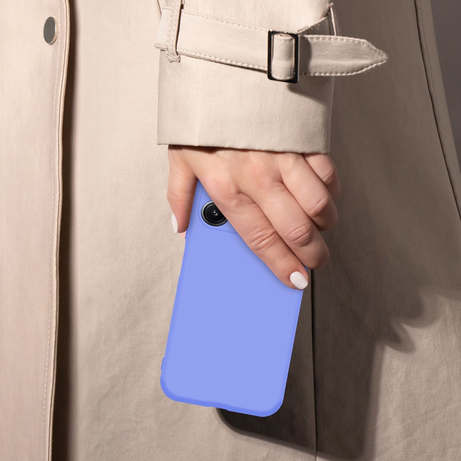 Eine Hand mit weiß lackierten Nägeln hält ein hellblaues Handy vor einem beigen Trenchcoat.