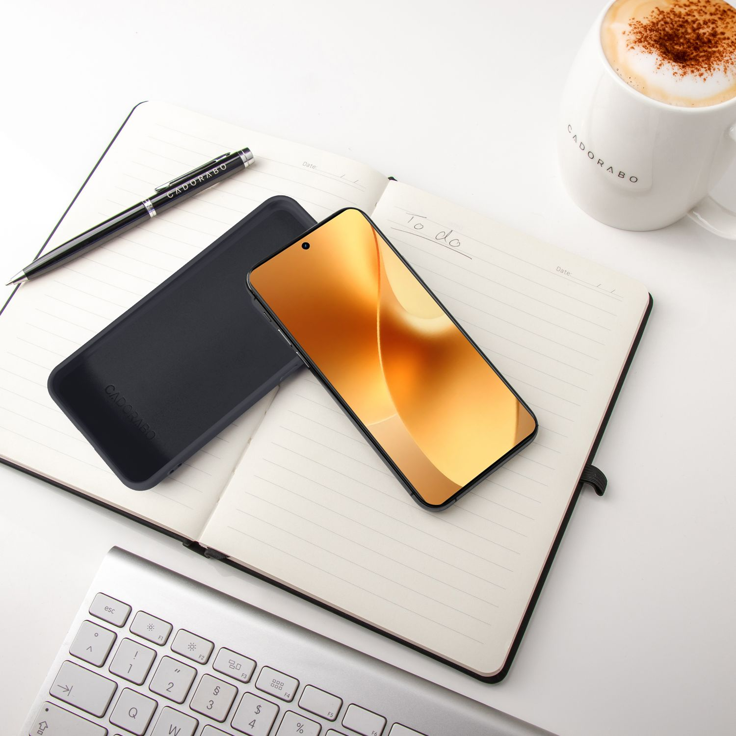 Ein Smartphone liegt auf einem Notizbuch neben einer Kaffeetasse.