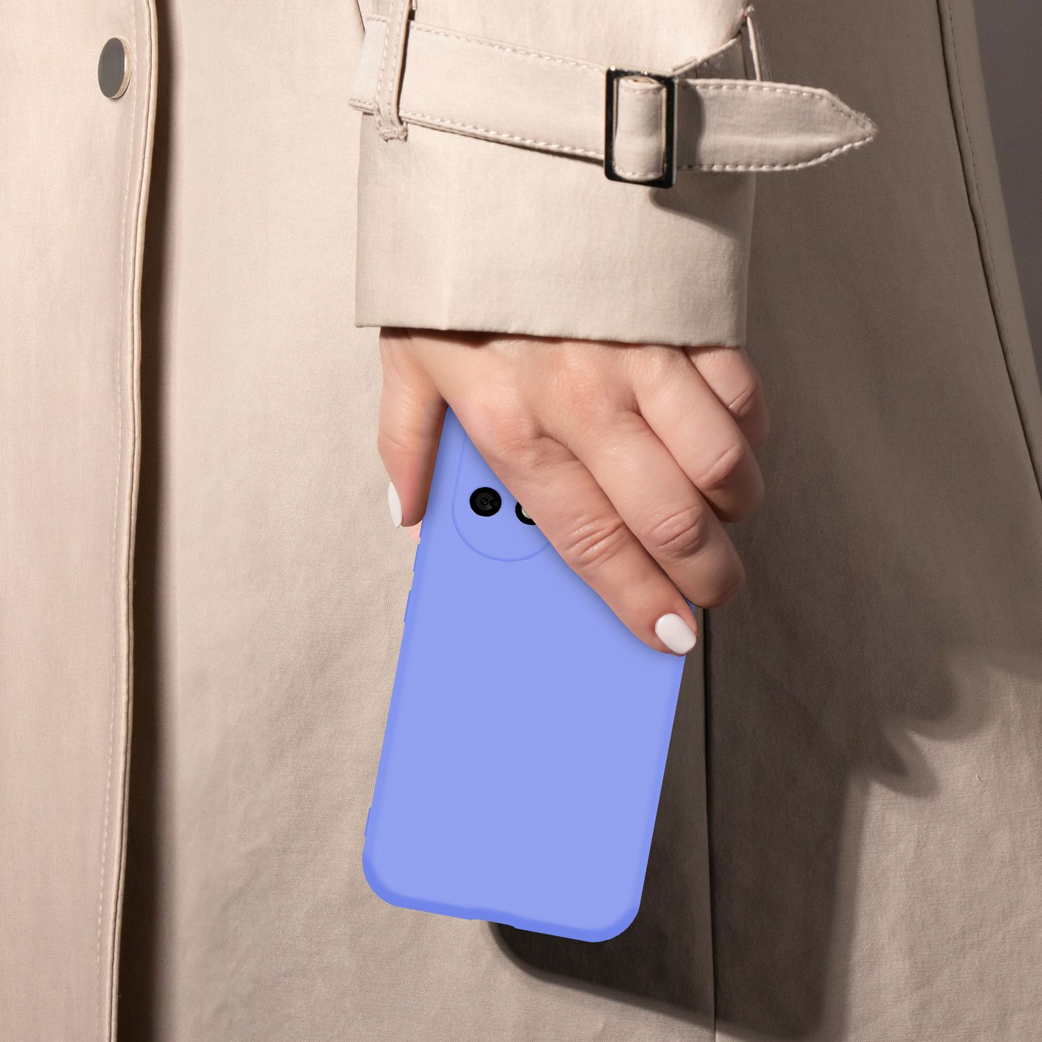 Eine Hand mit weiß lackierten Nägeln hält ein hellviolettes Smartphone vor einem beigen Trenchcoat.