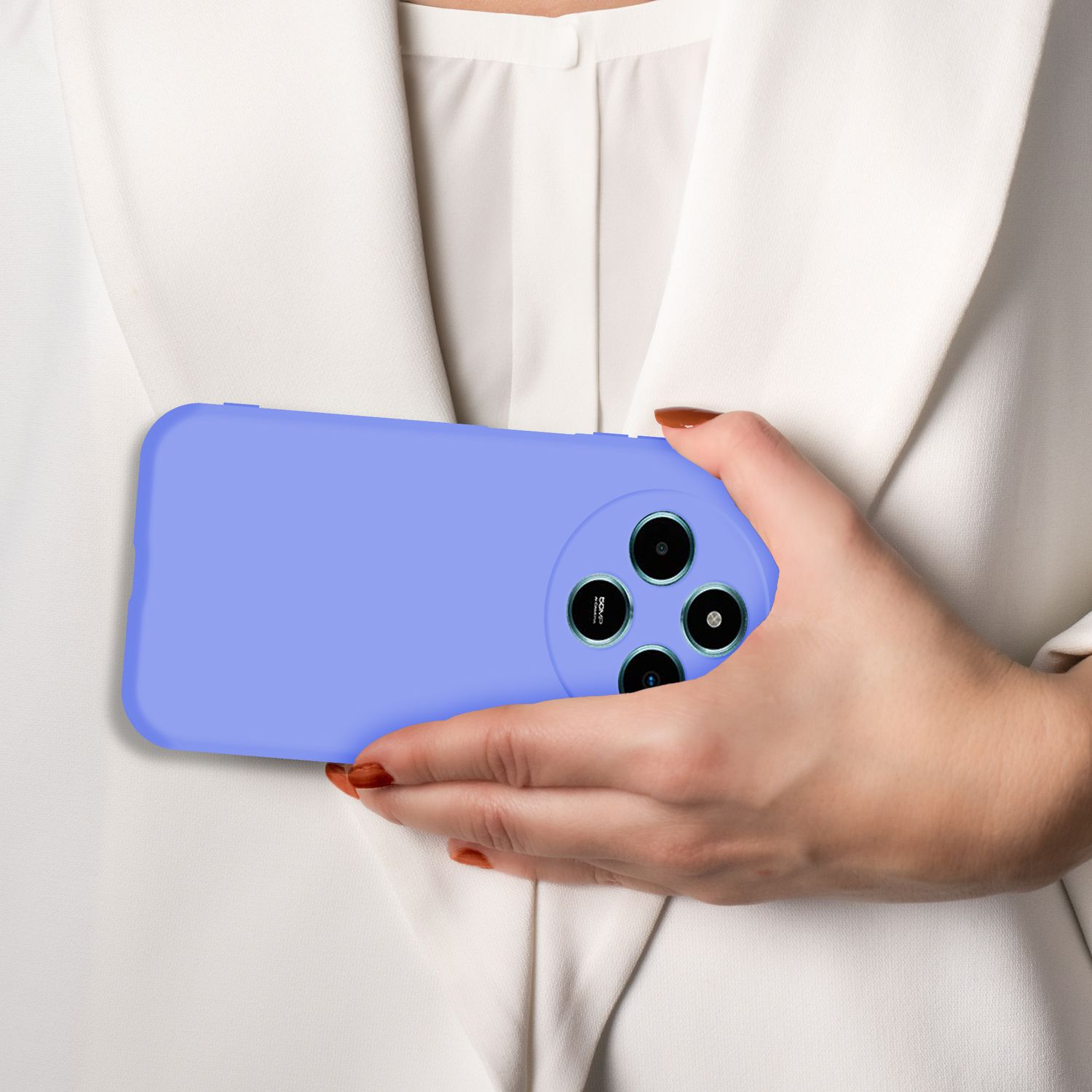 Eine Hand hält ein lila Handy mit vier Kameras vor einem weißen Blazer.