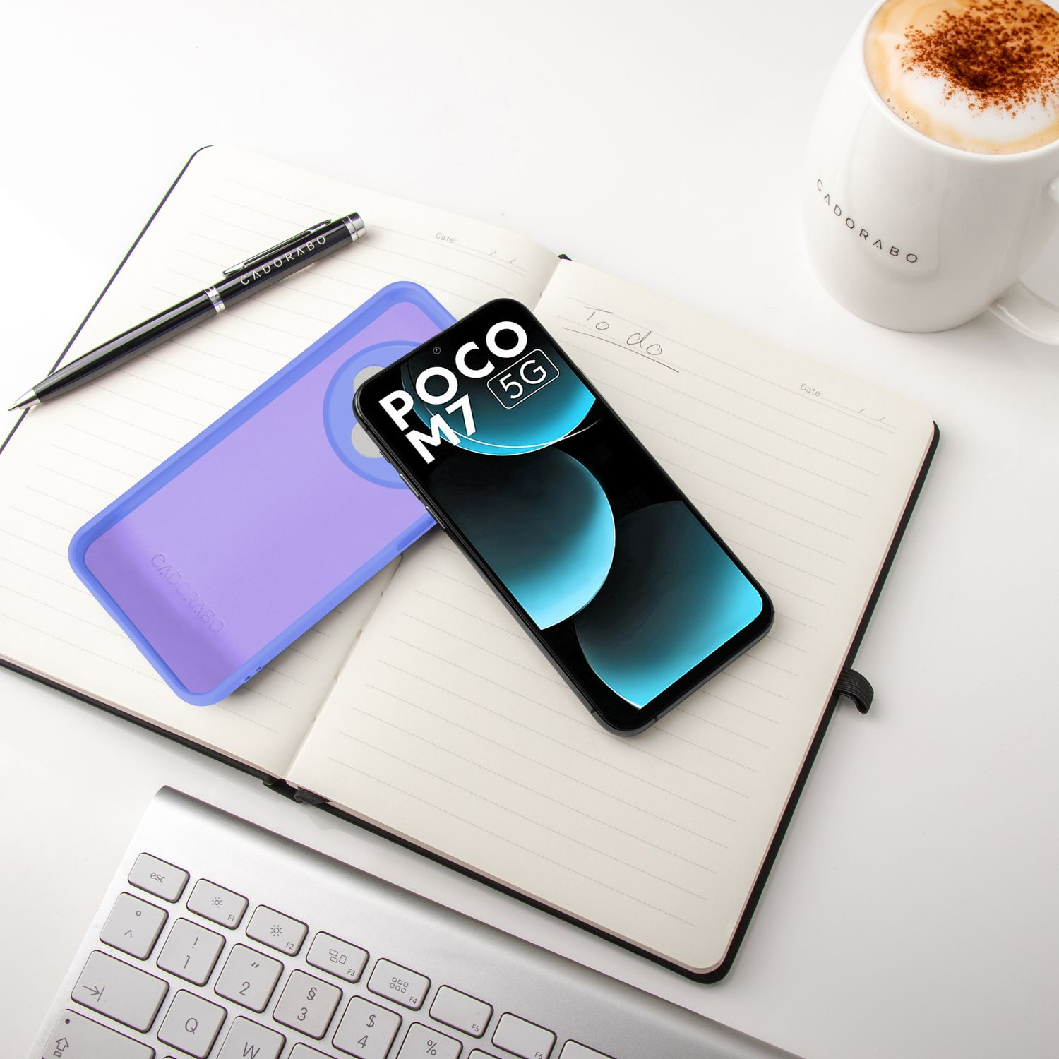 Ein Smartphone, eine Hülle, ein Notizbuch, ein Stift, eine Tastatur und eine Kaffeetasse.