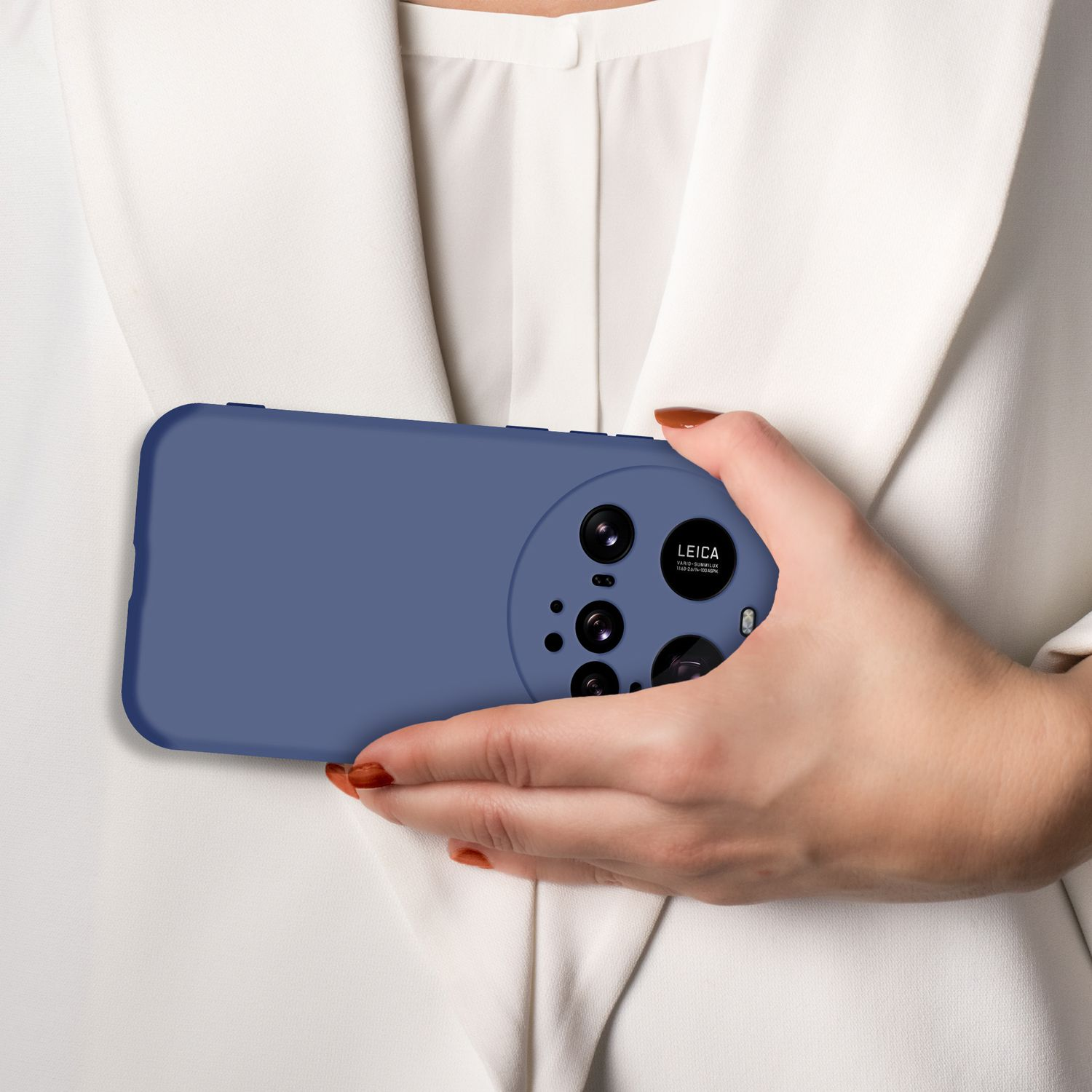 Eine Hand hält ein blaues Handy mit vier Kameras vor einem weißen Hemd.