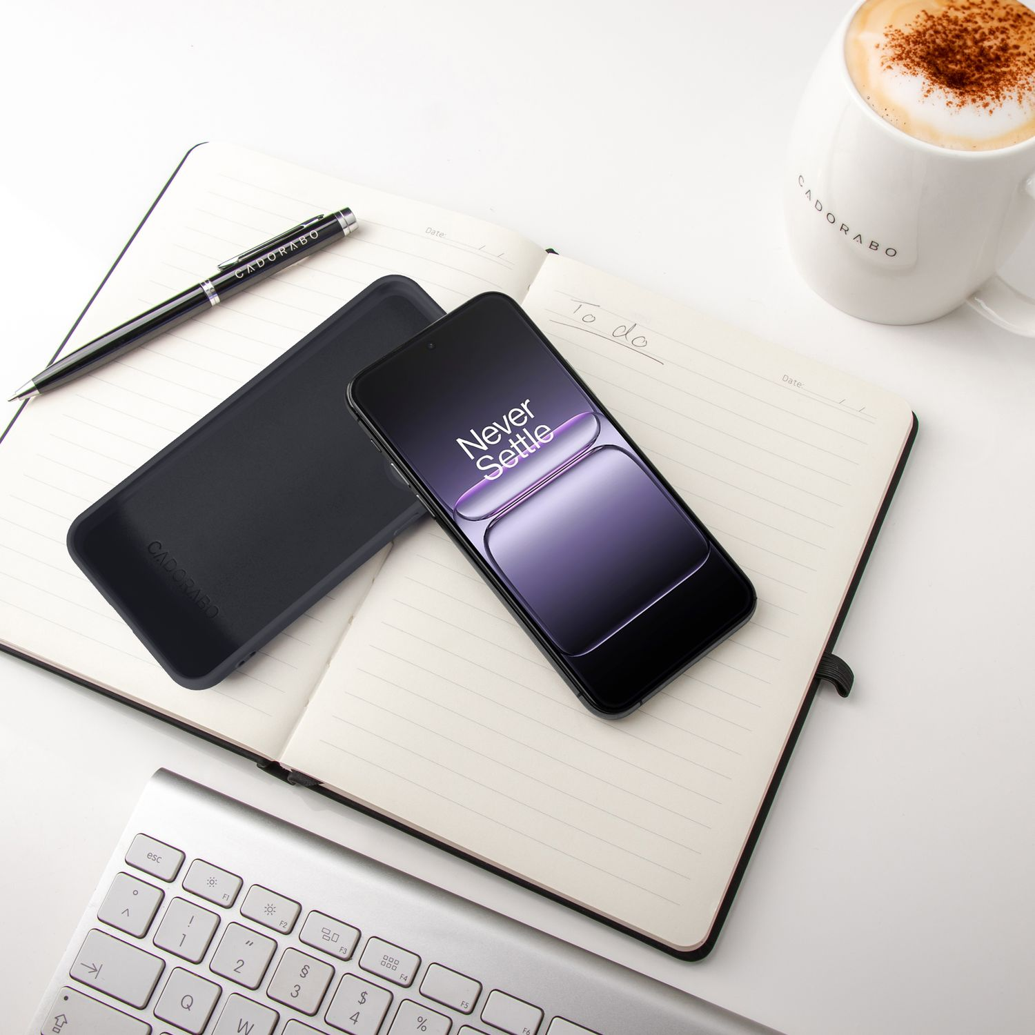 Ein Smartphone auf einem Notizbuch mit einer Tasse Kaffee und einer Tastatur.