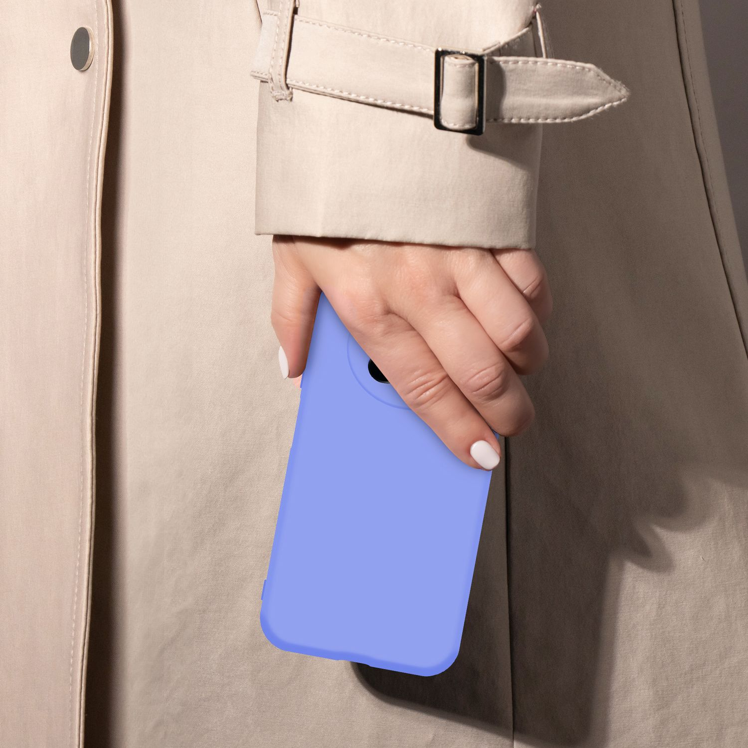 Eine Hand mit weißen Nägeln hält ein lila Handy vor einem beigen Mantel.