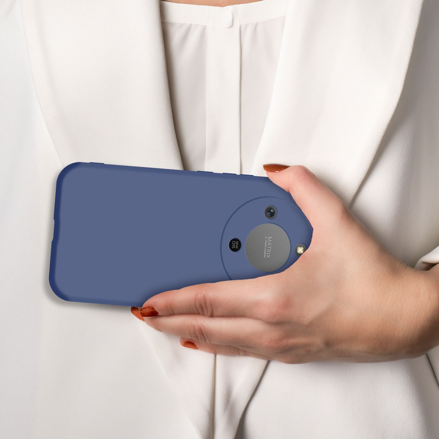 Eine Hand hält ein blaues Smartphone mit dreifacher Kamera vor einem weißen Hemd.