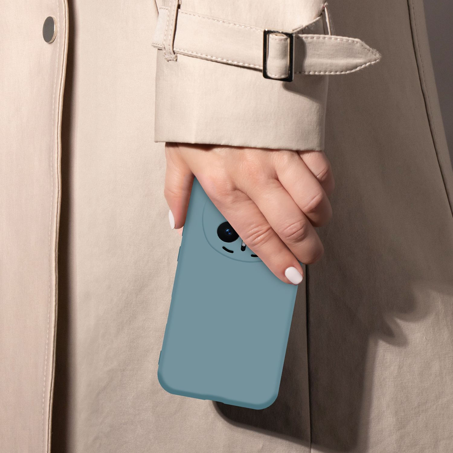 Eine Hand mit blauem Handy in einem beigefarbenen Trenchcoat.