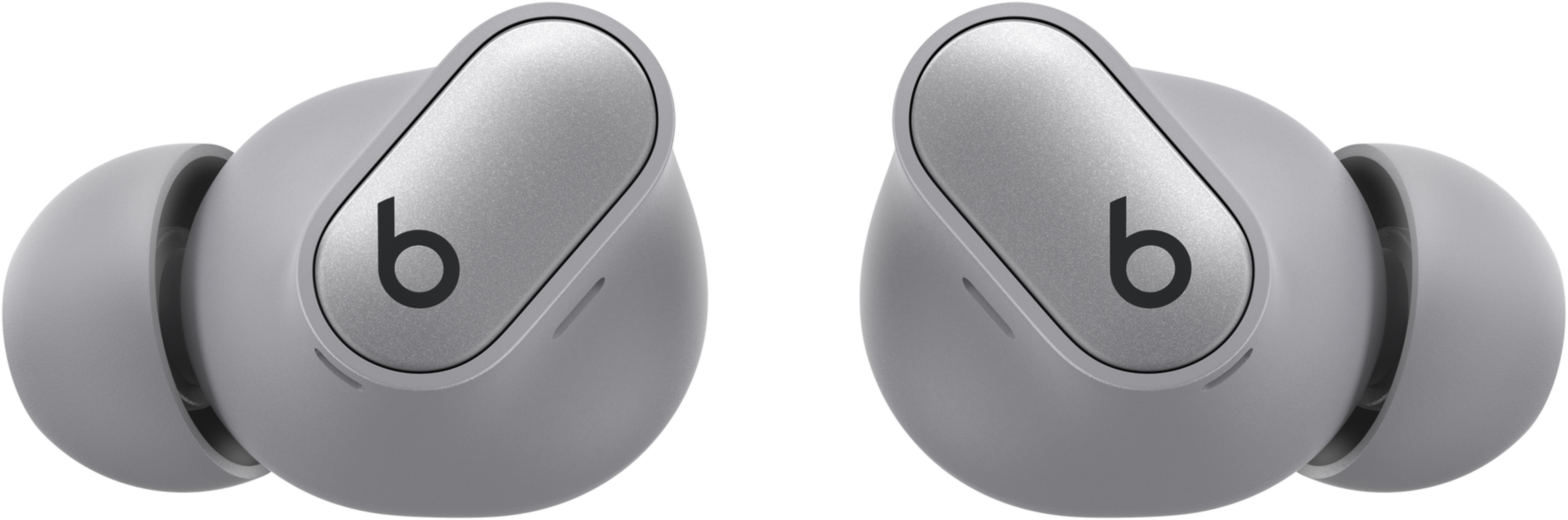Dwa szare słuchawki Beats z srebrnymi akcentami i czarnym logo 'b'.