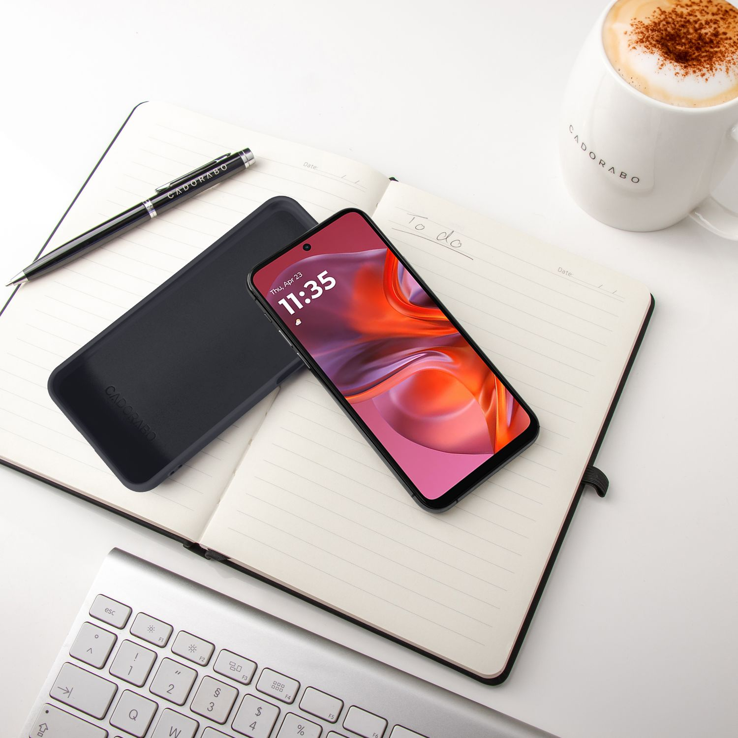 Ein offenes Notizbuch mit einem Smartphone, Stift, Handyhülle und Kaffee.