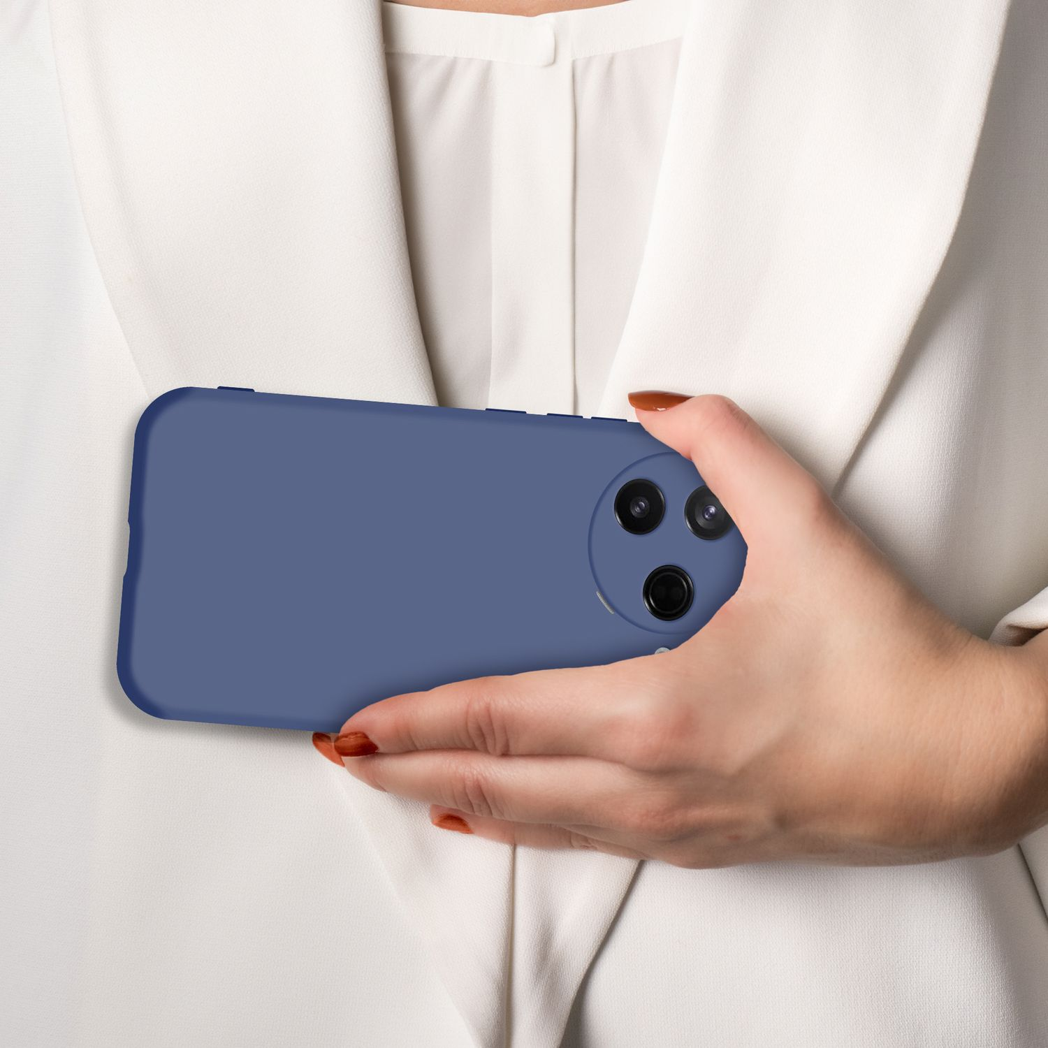 Eine Hand hält ein blaues Handy mit drei Kameras vor einem weißen Hemd.
