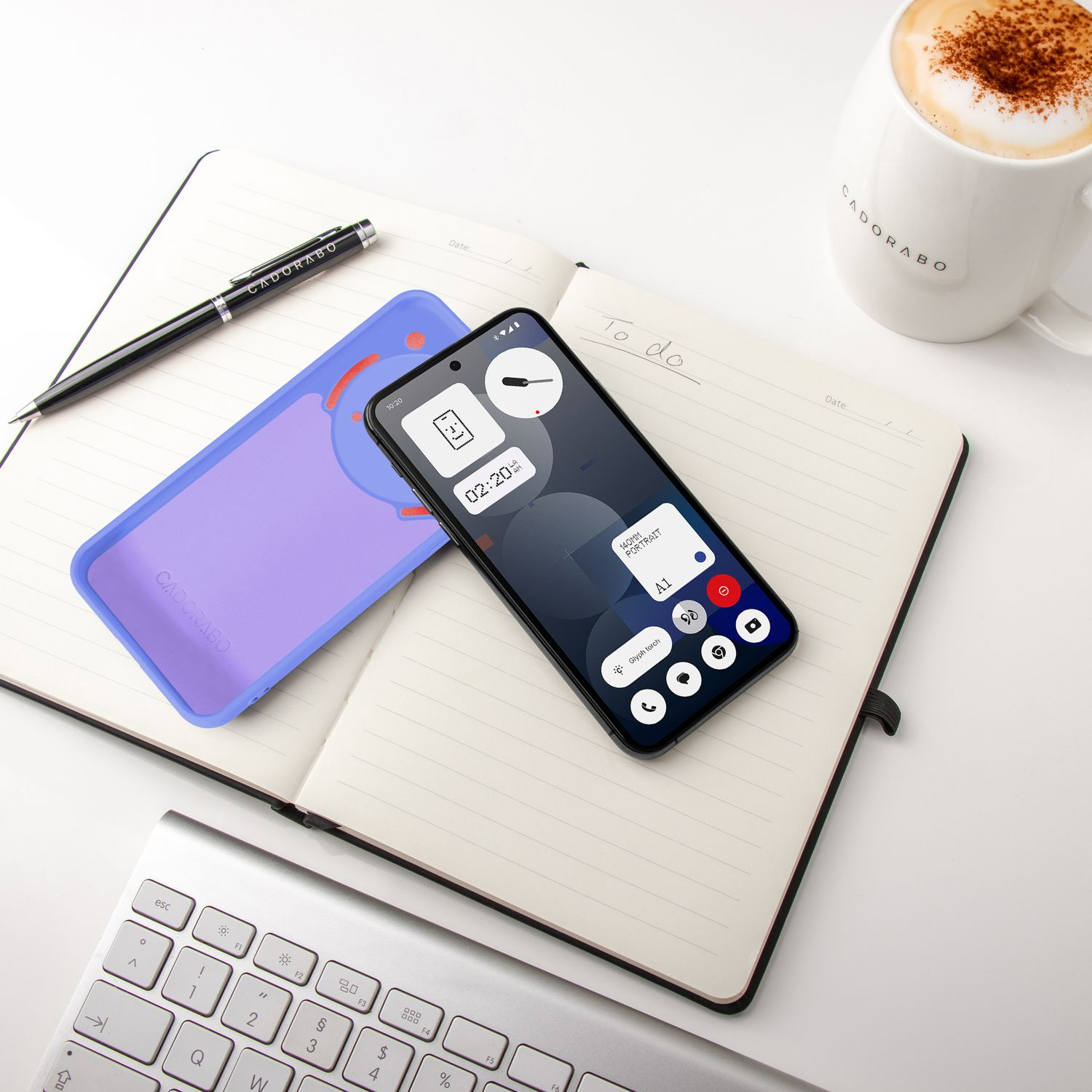 Ein Smartphone liegt auf einem Notizbuch neben einer Tasse Kaffee und einer Tastatur.