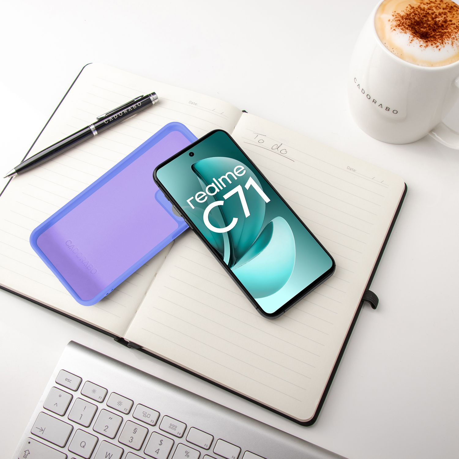 Ein Smartphone mit Realme C71 liegt auf einem Notizbuch neben einer Kaffeetasse und Tastatur.