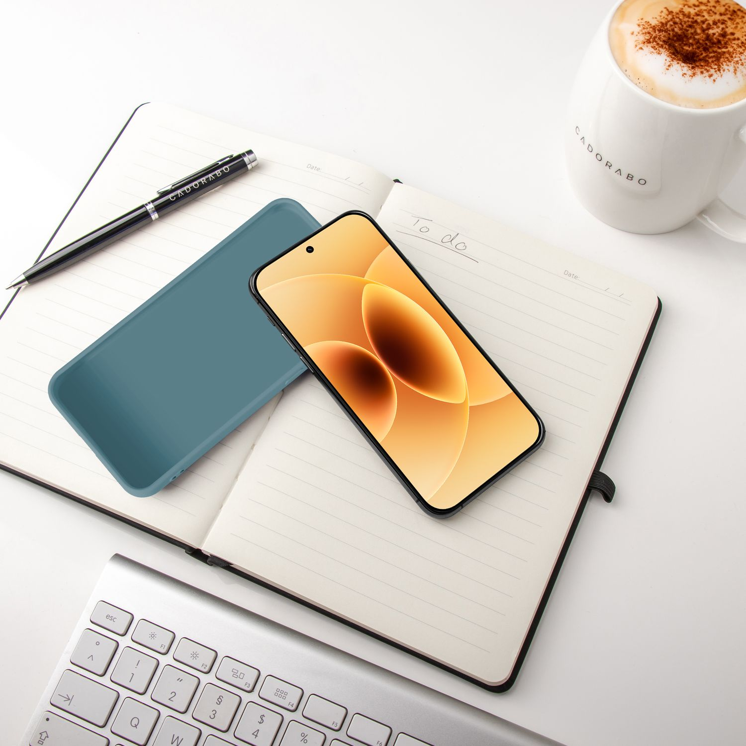 Ein Smartphone auf einem Notizbuch mit einer Tasse Kaffee und Tastatur.