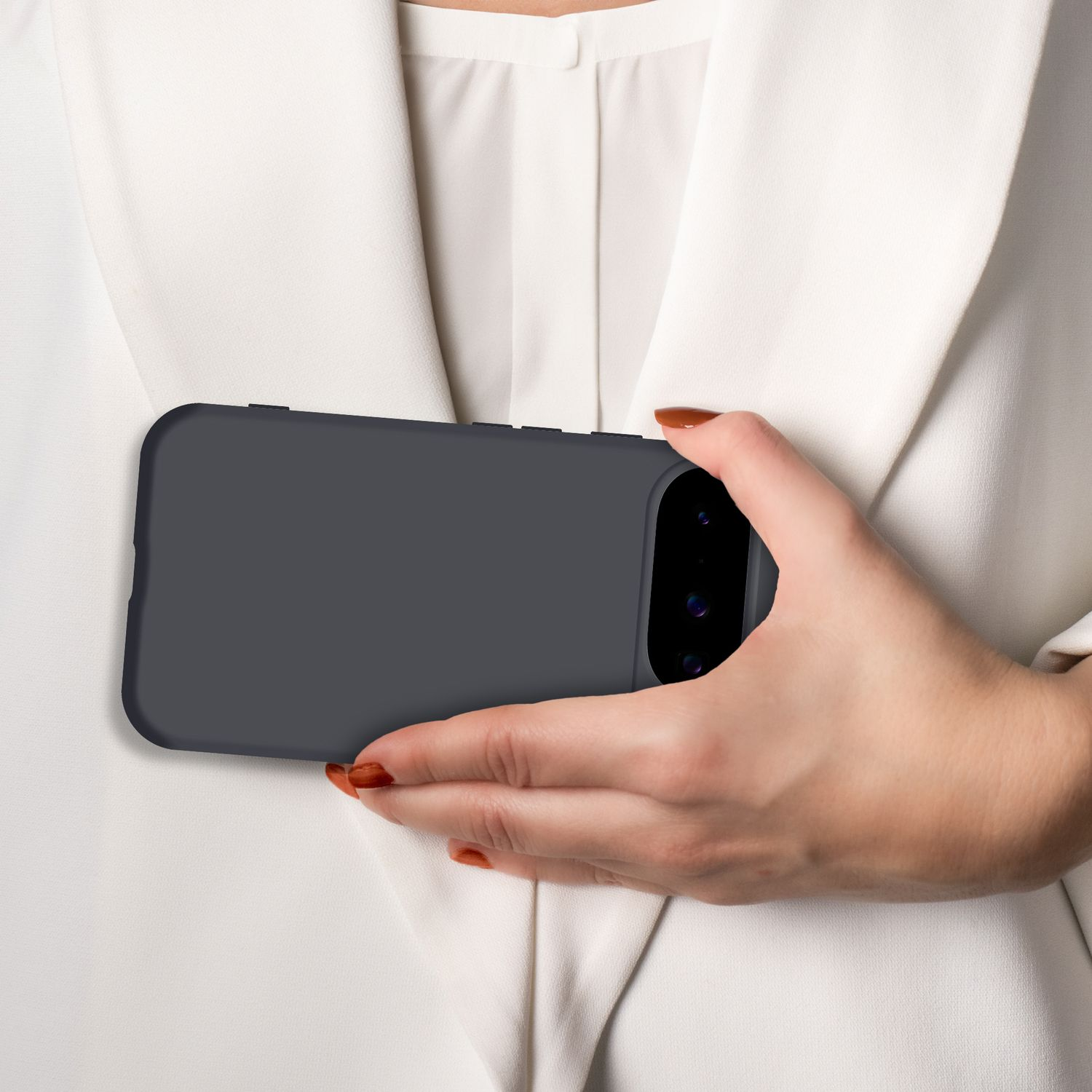 Eine Hand hält ein dunkles Smartphone vor einem weißen Kleid.