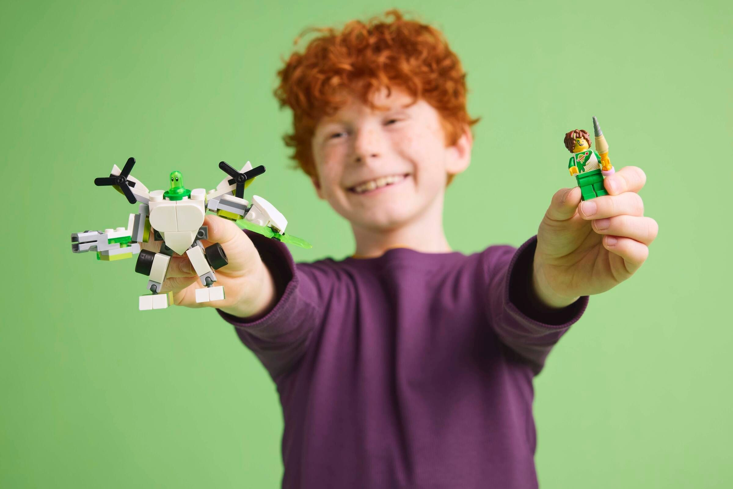 Un ragazzo rosso tiene un aereo Lego e una figura Lego.