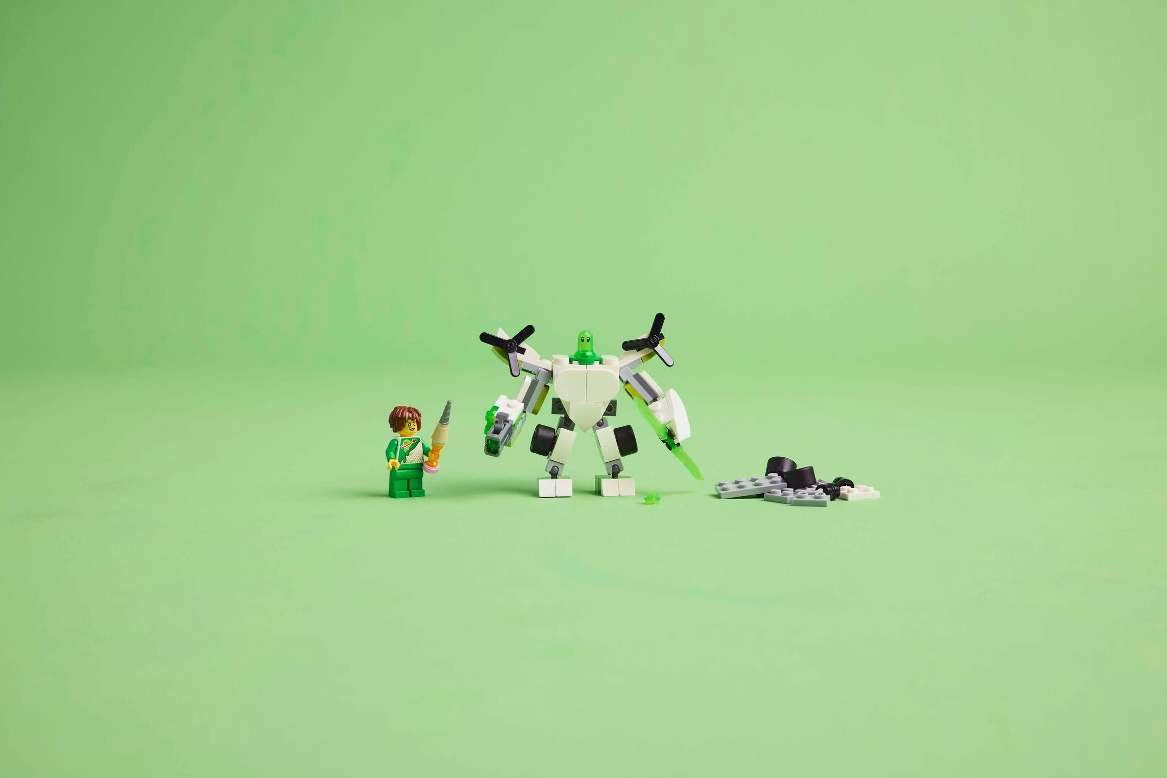 Una figura Lego accanto a un robot bianco con accenti verdi.
