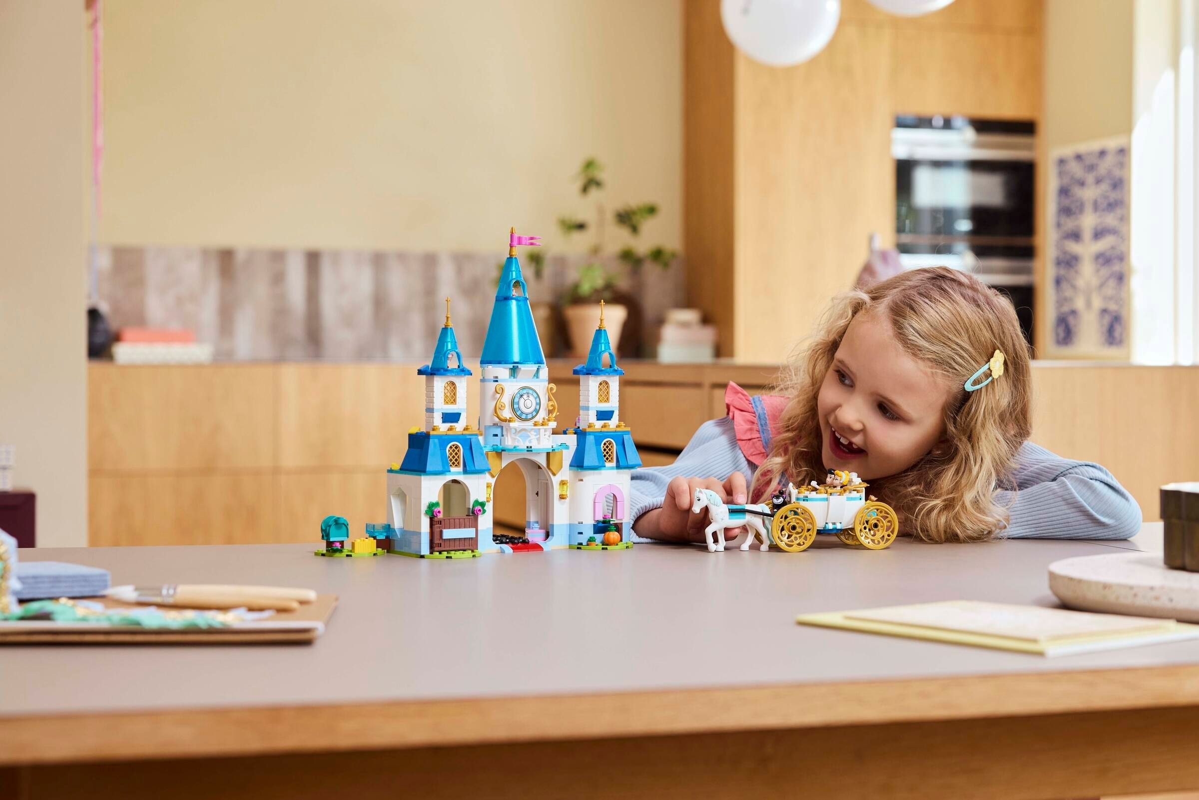 Ein Mädchen spielt mit einem Lego-Schloss und einer Kutsche mit einem weißen Pferd.