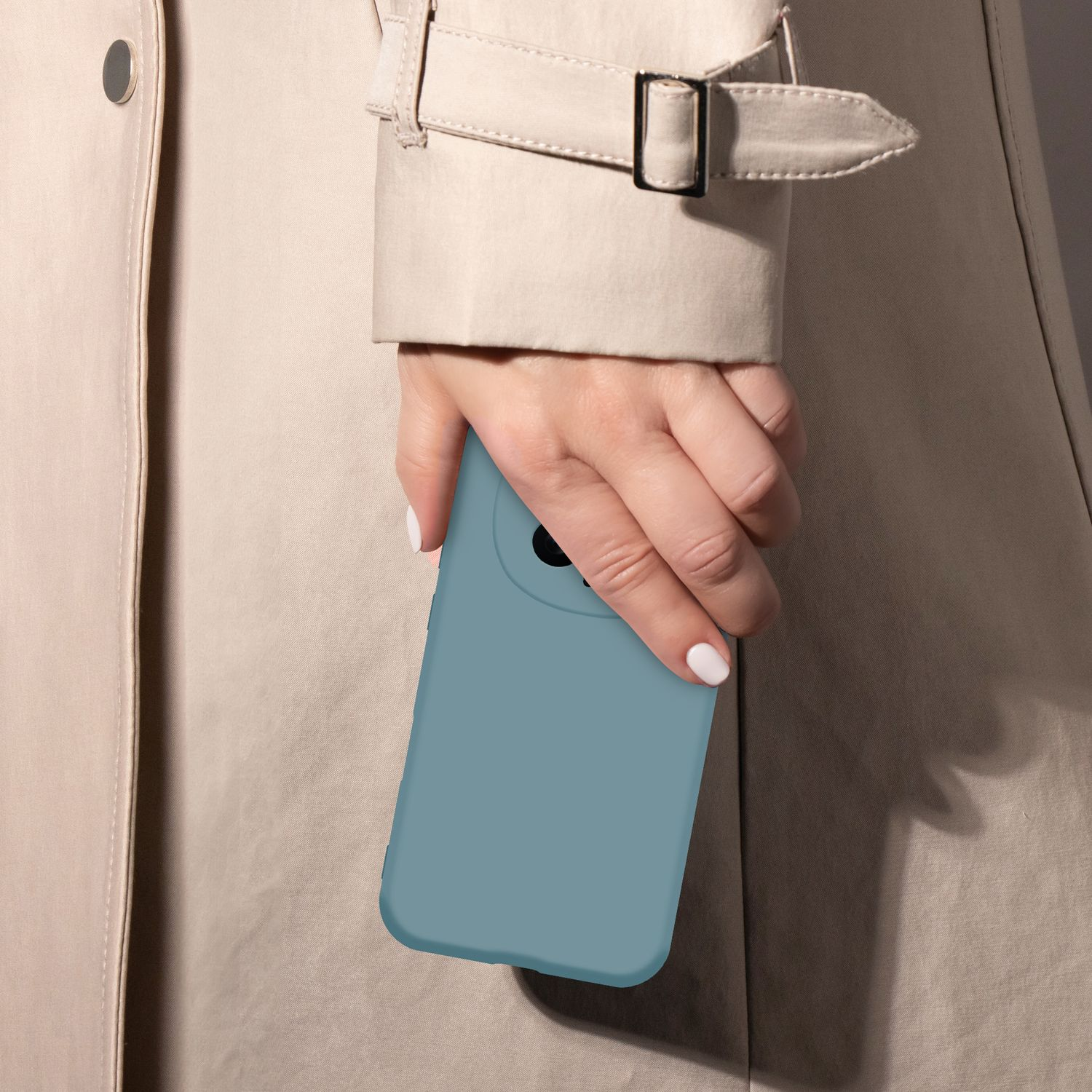 Eine Hand mit blauer Hülle hält ein Smartphone vor einem beigen Mantel.