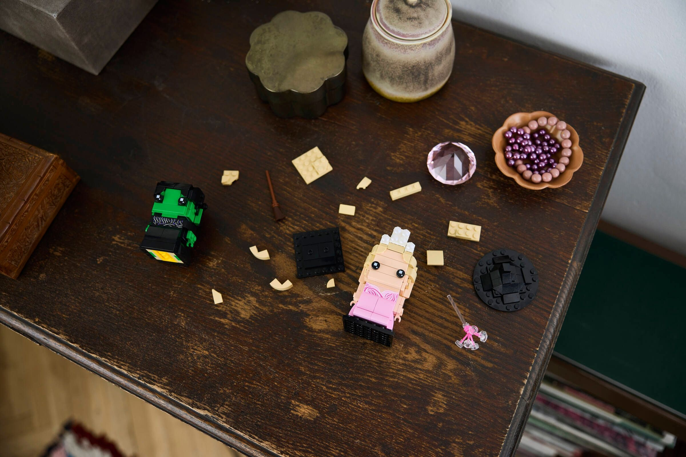 Lego-Figuren, ein grüner und ein pinker, liegen auf einem Holztisch.