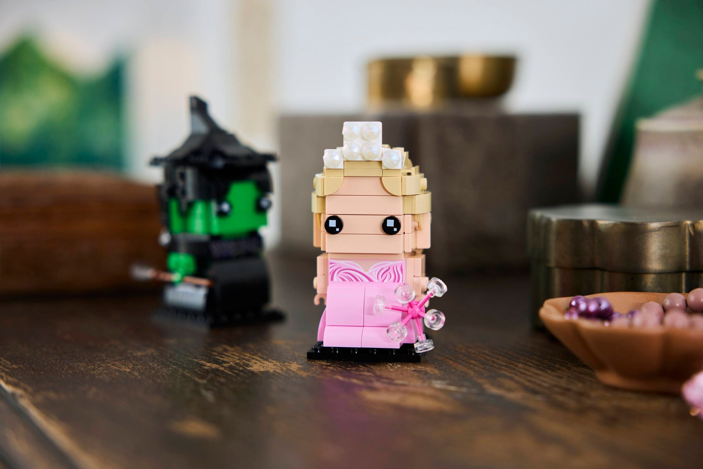 Zwei Lego-Figuren, eine Hexe und eine Prinzessin, stehen auf einem Holztisch.