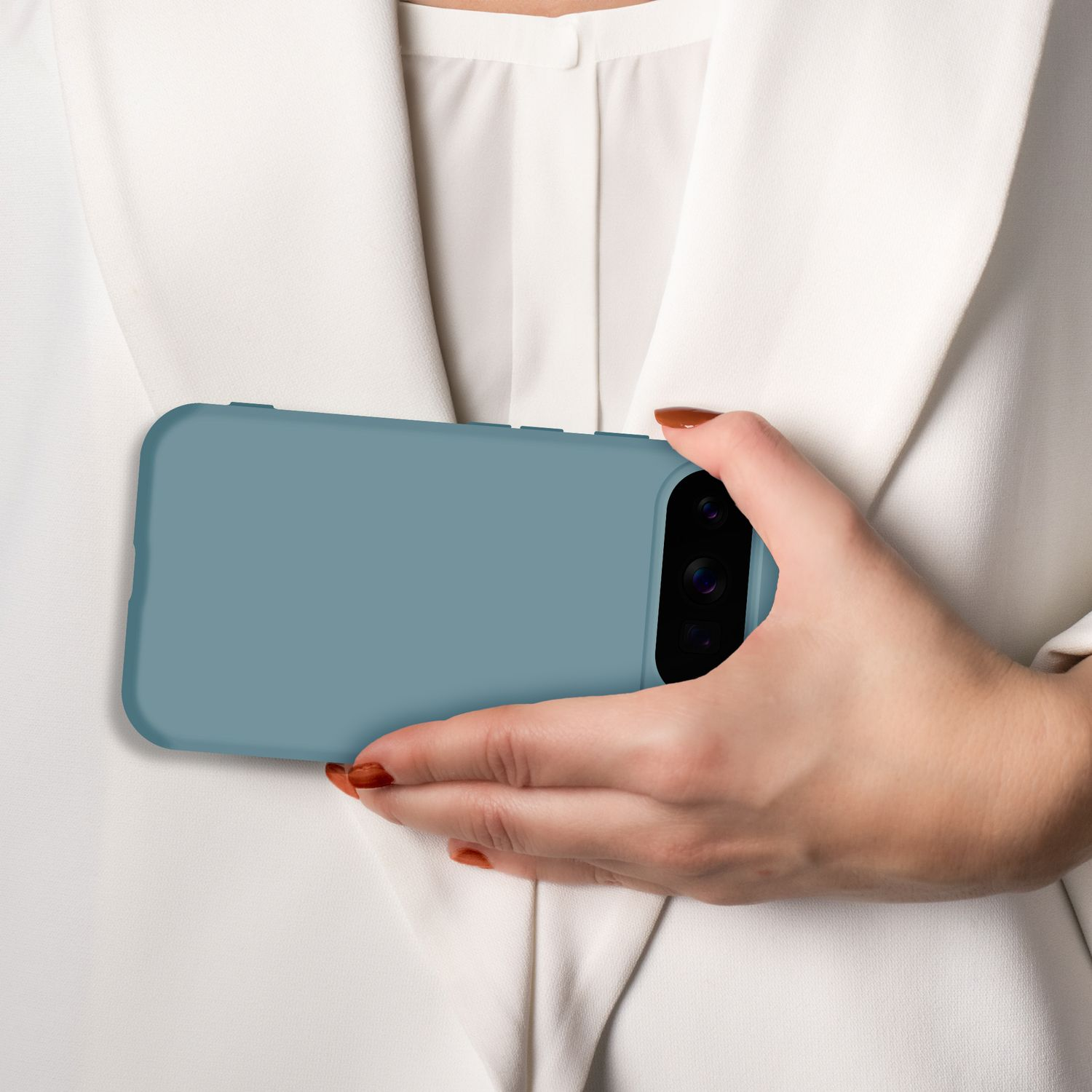 Eine Hand hält ein blaues Handy vor einem weißen Blazer.