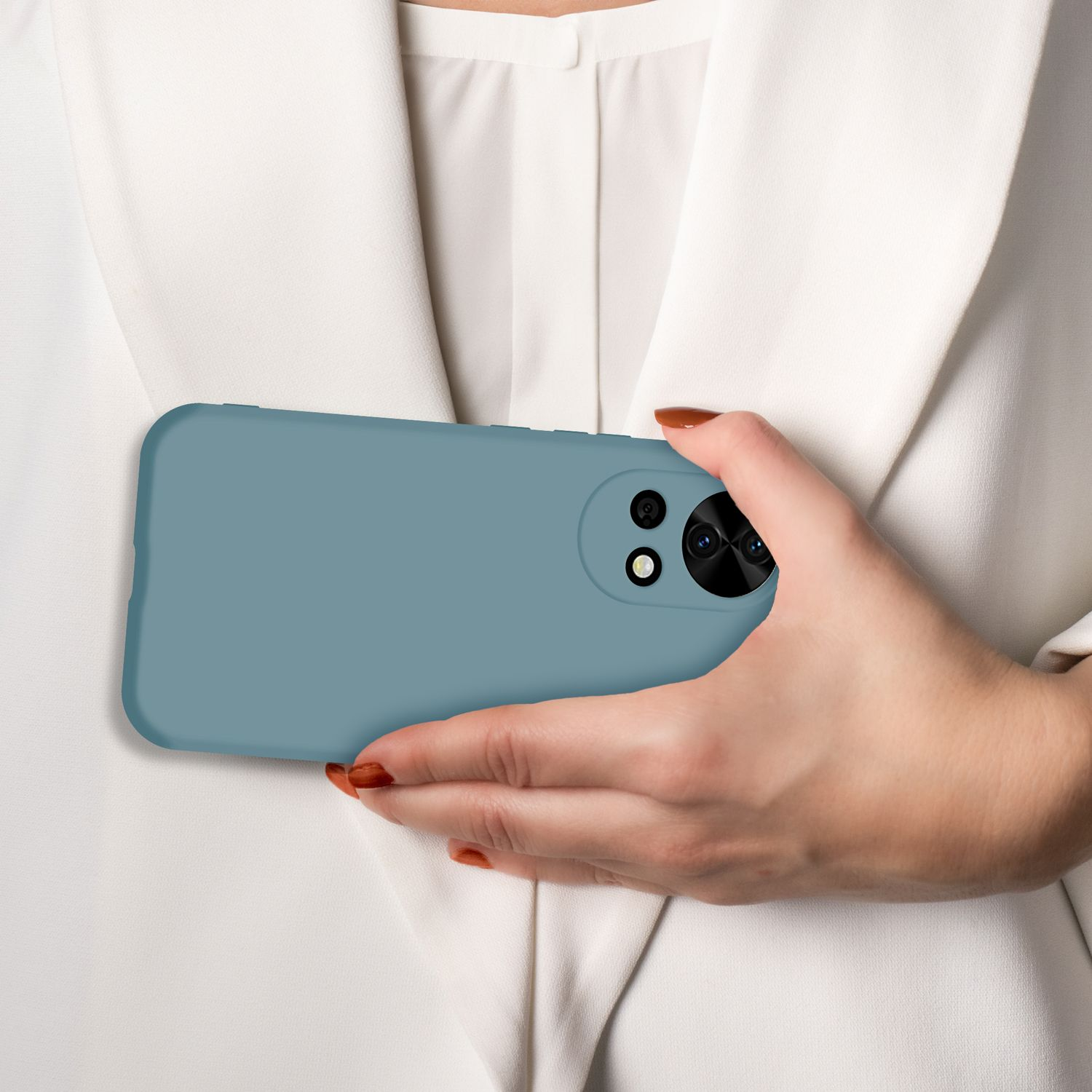Eine Hand hält ein blaues Smartphone mit drei Kameras vor einem weißen Hemd.