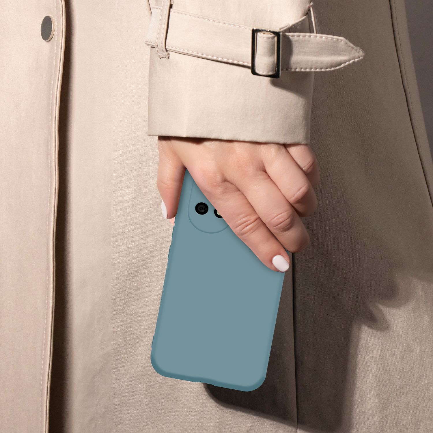 Eine Hand hält eine blaue Handyhülle vor einem beige Trenchcoat.