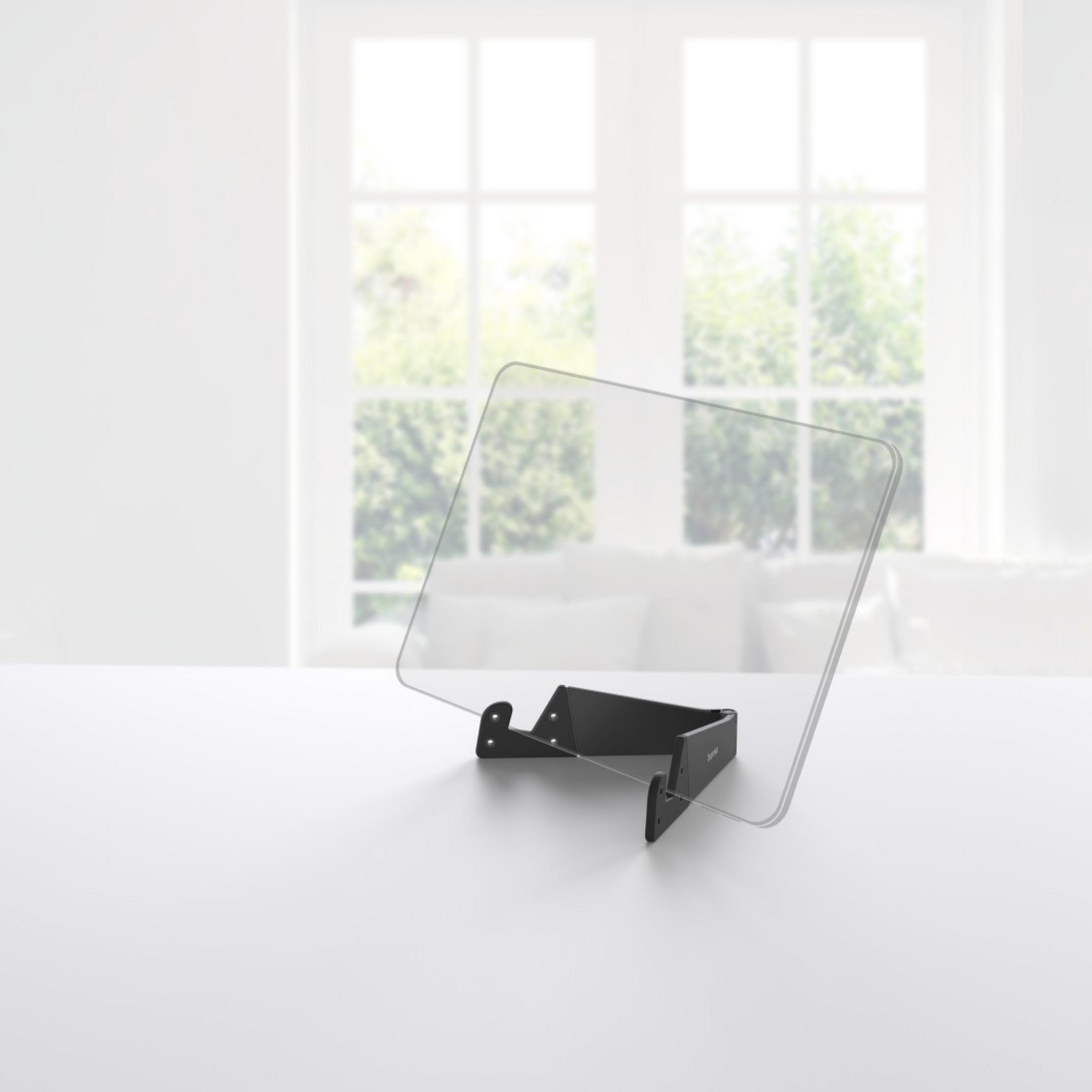 Ein transparenter Bildschirm auf einem schwarzen Ständer auf einem weißen Tisch.