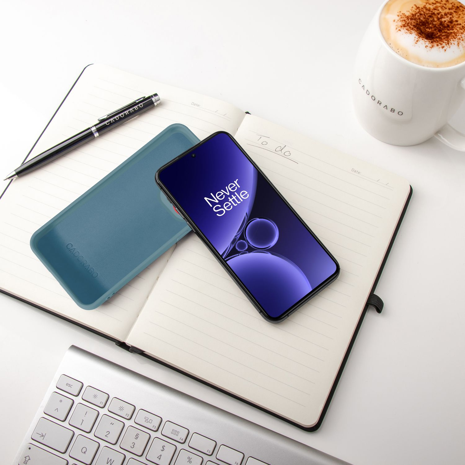 Ein Smartphone, Notizbuch, Stift und Kaffee auf einem Schreibtisch.