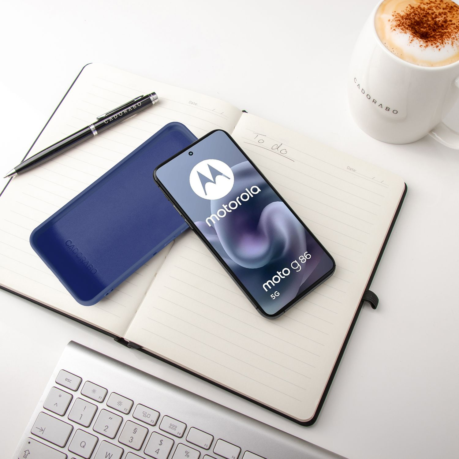Ein Motorola-Handy auf einem Notizbuch mit Stift, Tastatur und Kaffee.