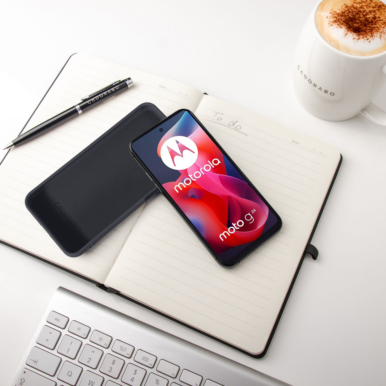 Ein Motorola-Handy liegt auf einem Notizbuch neben einer Tasse Kaffee.