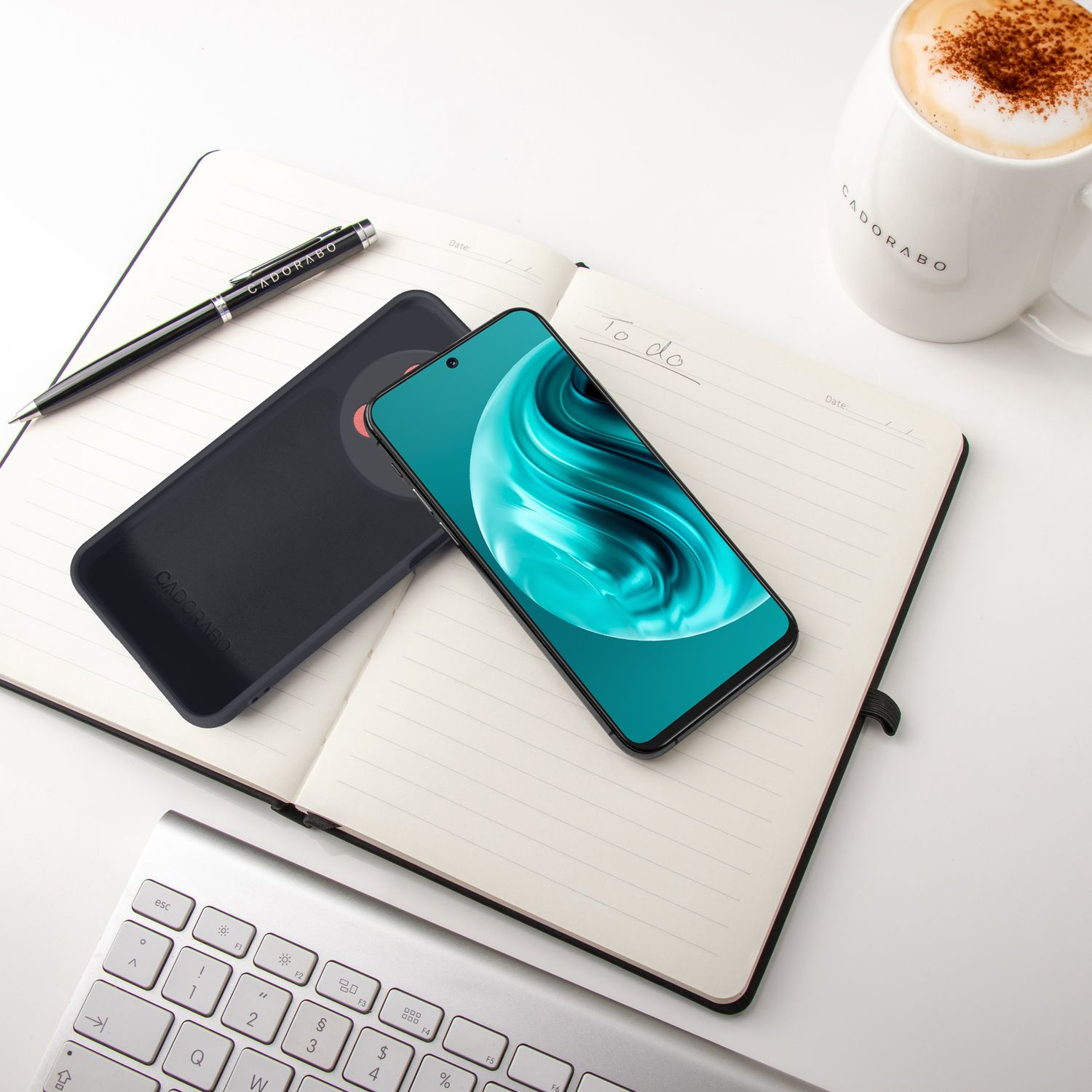 Ein aufgeschlagenes Notizbuch mit einem Smartphone, einer Kaffeetasse und Tastatur.