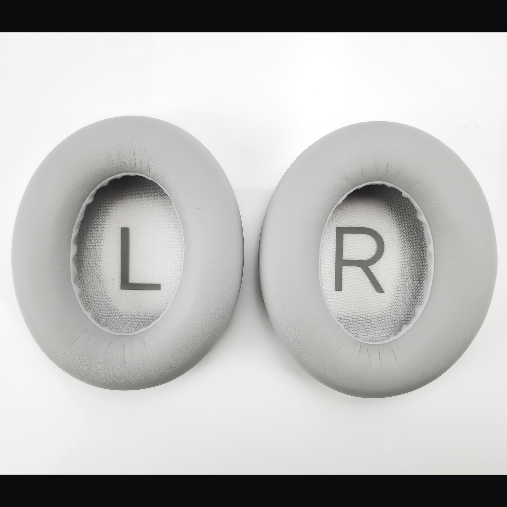 Dwie szare poduszki na słuchawki, oznaczone L po lewej i R po prawej.