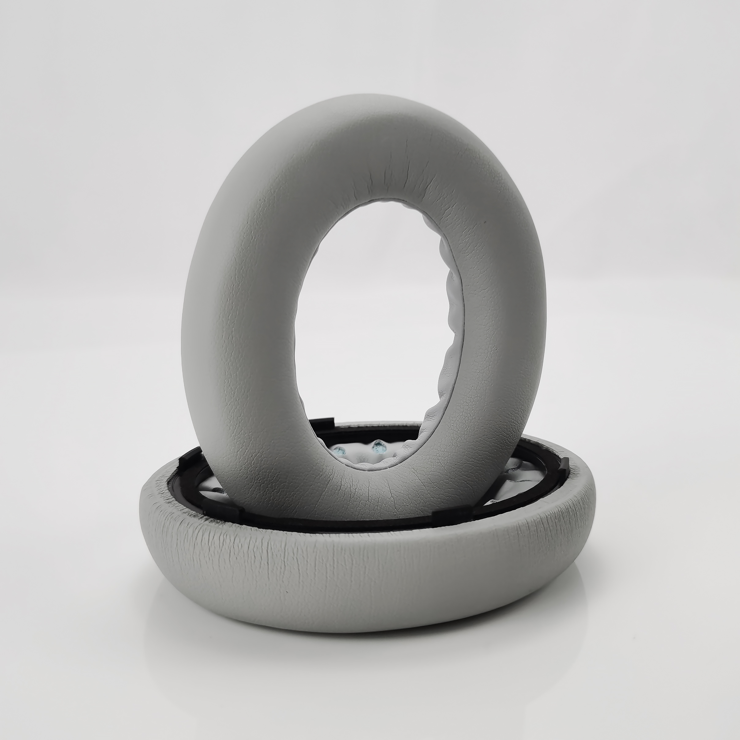 Szare poduszki nauszne do słuchawek na białym tle.