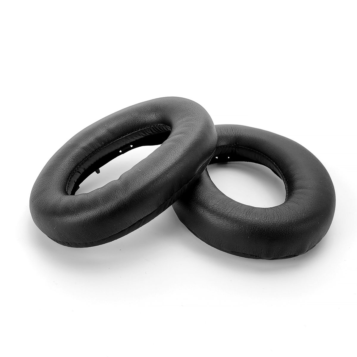 Dwie czarne, owalne nauszniki leżą obok siebie na białym tle.