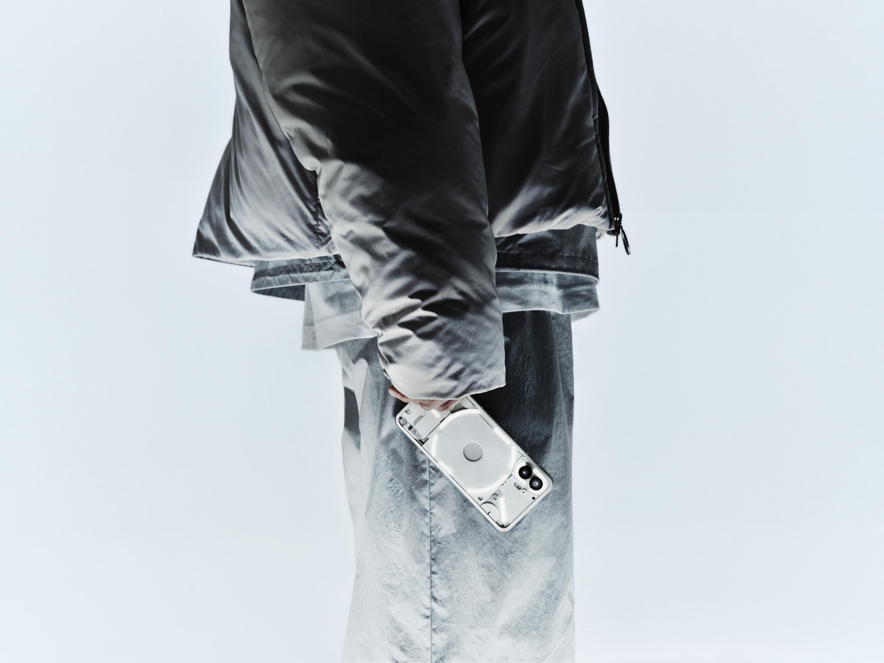 Eine Person hält ein transparentes Smartphone mit rundem Lichtring in der Hand.
