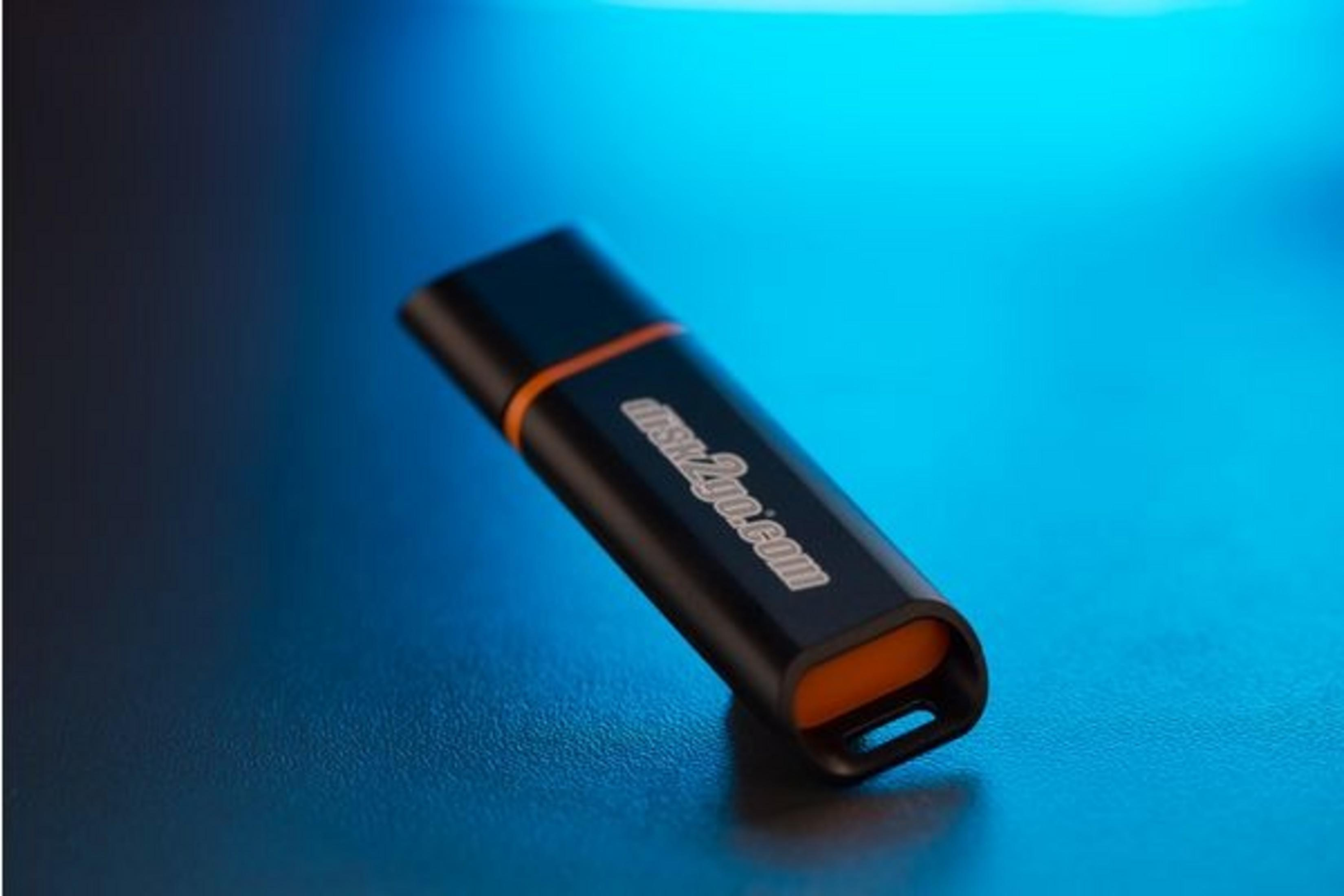Une clé USB noire avec des accents orange repose sur une surface bleue.