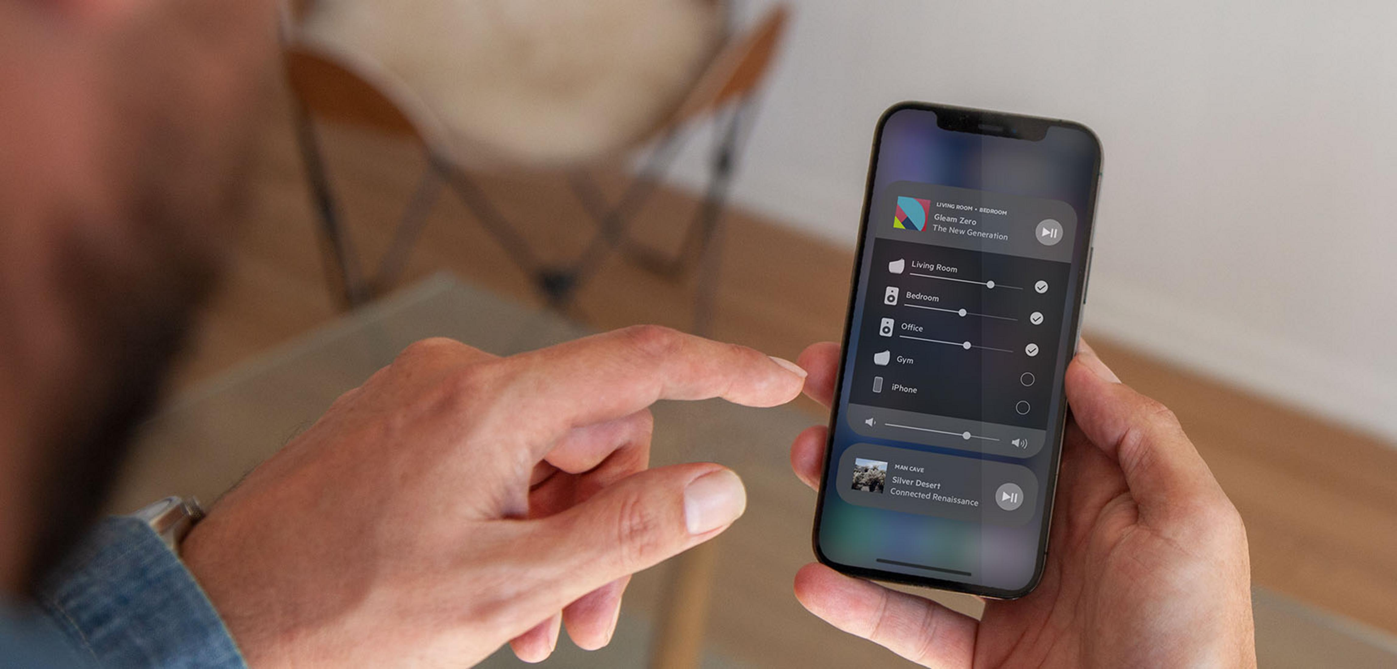Ein Mann bedient ein Smartphone mit einer App zur Steuerung von Räumen und Musik.