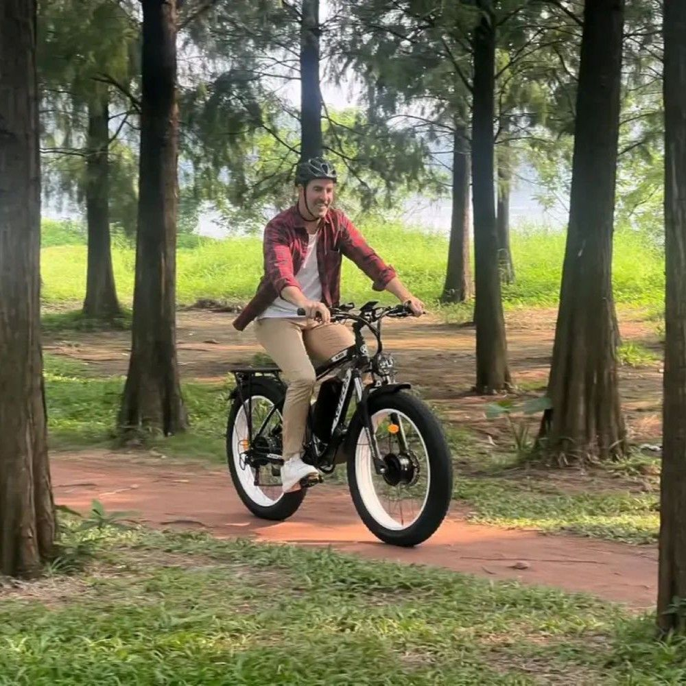 Un uomo guida una e-bike nera su un sentiero rosso nel bosco.