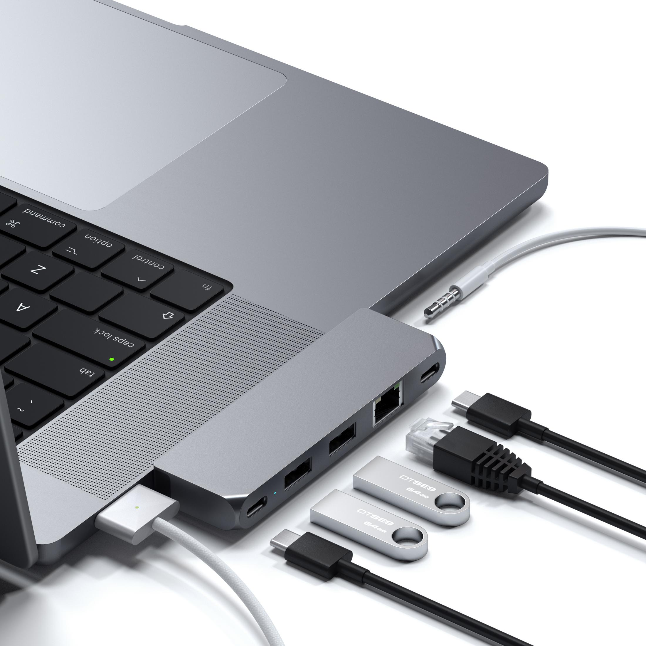 Laptop argento con hub USB-C, chiavette USB e cavi su sfondo bianco.